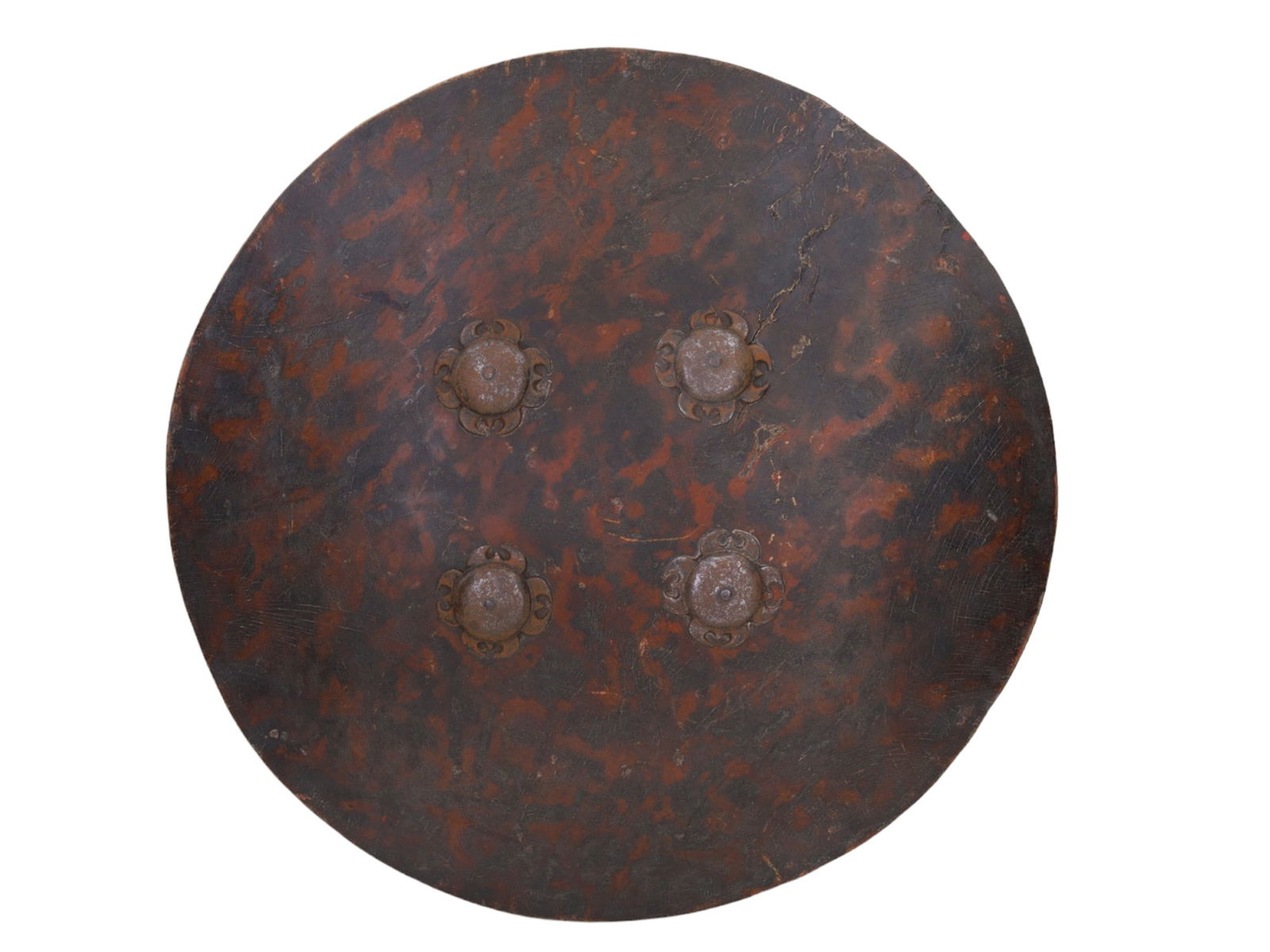AN INDIAN HIDE-WRAPPED DHAL SHIELD, 19TH CEN.: Consisting of hide in imitation of a tortoiseshell pattern and mounted with four steel bosses, each with hooked quatrefoil borders, the interior retaining its leather pad and grips. D: 18 3/8 in., (46