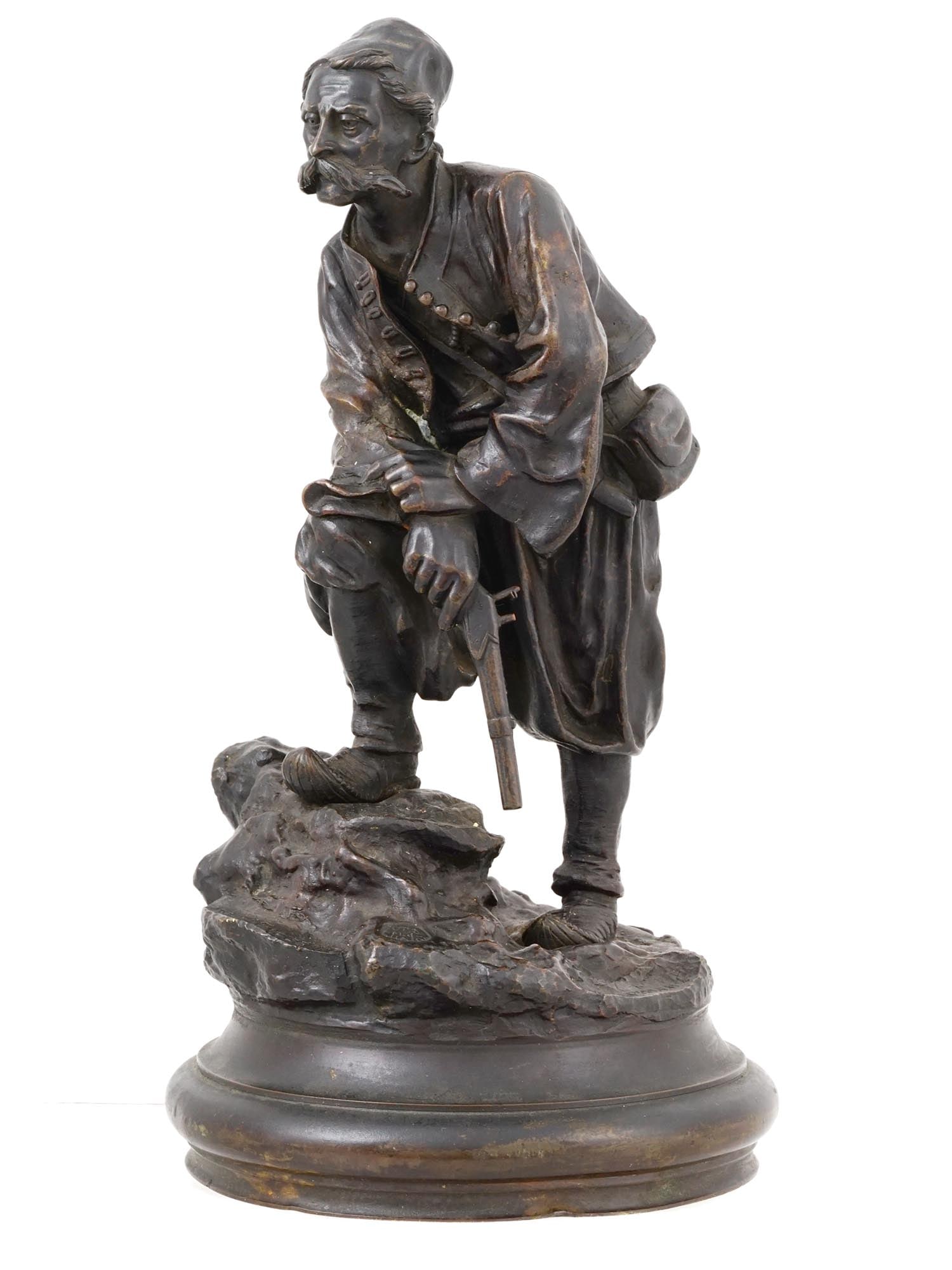 A RUSSIAN BRONZE FIGURE BY GRACHEV "A BULGARIAN", CA. 1870: A Russian bronze by the Grachev Brothers titled "A BULGARIAN" depicts a resting man holding a pistol lowered, modeled on a rocky naturalistic base, signed Grachev Brothers, mounted on a circular plint