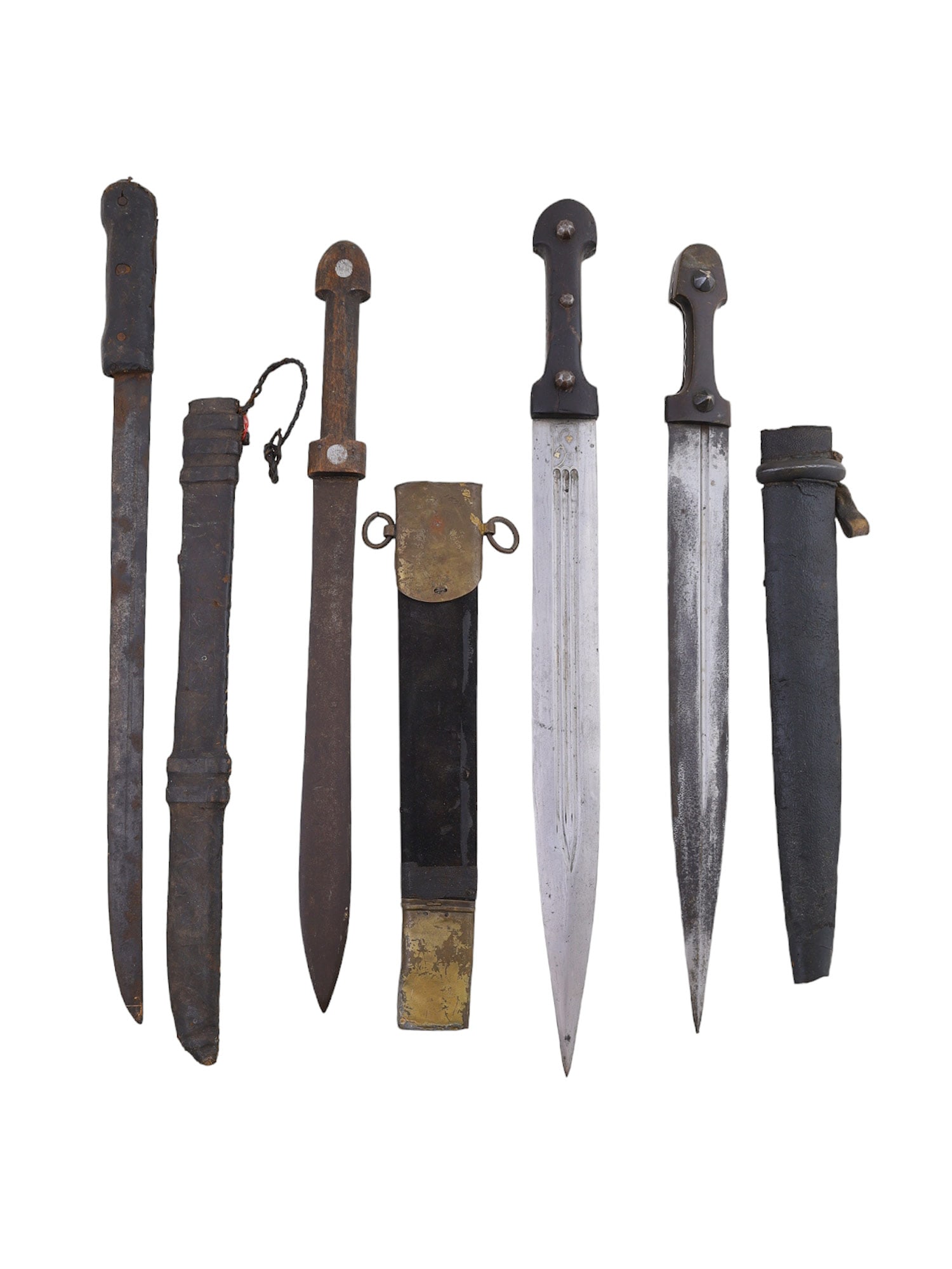 A LOT OF 3 KINDJAL DAGGERS AND A MACHETE, 19TH/20TH CENTURY: The kindjals are all of a triangular shape with wooden hilts. The scabbards do not appear to be the original make for the blades. One is leather with a steel ring and the other is leather with brass m
