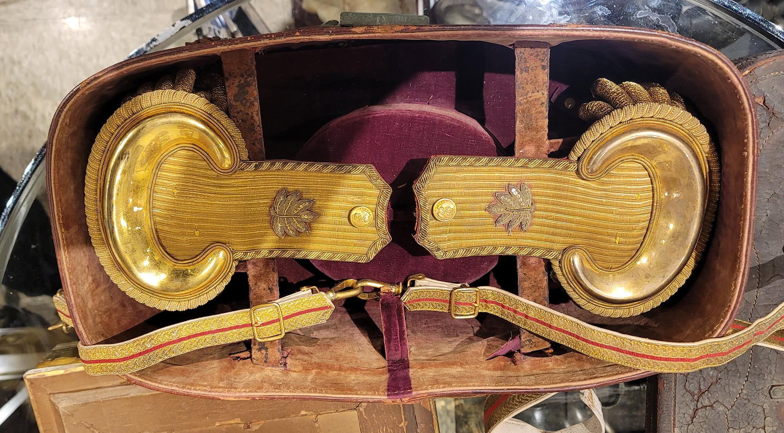 AN AMERICAN CASED PAIR OF EPAULETS WITH GILT-BRONZE BELT, 19TH CEN.: A pair of 19th-century American epaulets with their accompanying gold, red-striped belt, all kept within their original fabric-lined leather case. The leaves on the boards may designate this as belong