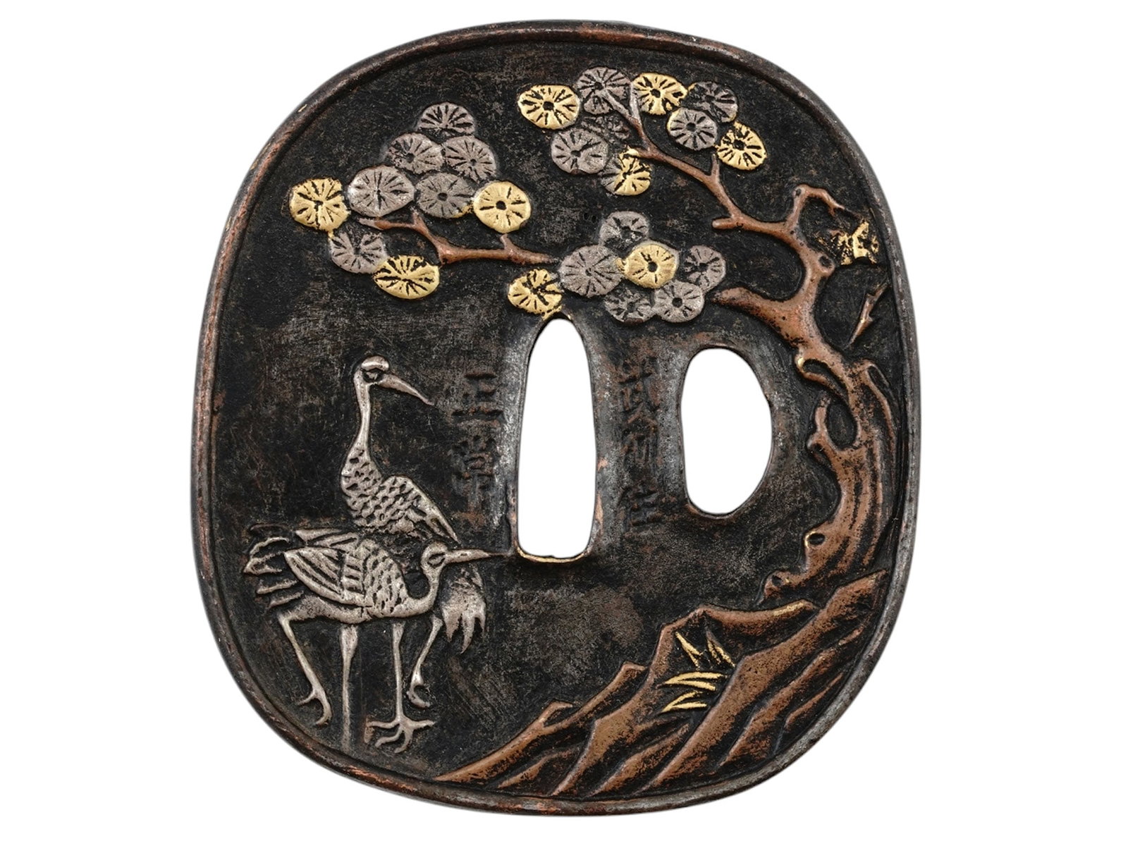 A LARGE SIGNED JAPANESE TSUBA WITH SILVER INLAID CRANES: A signed Tsuba of nagamaru gata in shakudo and decorated in takazogan with gold and silver images of cranes under tree branches in bloom. Signed along the blade slot on the reverse. Dimensions: 3 1/8 