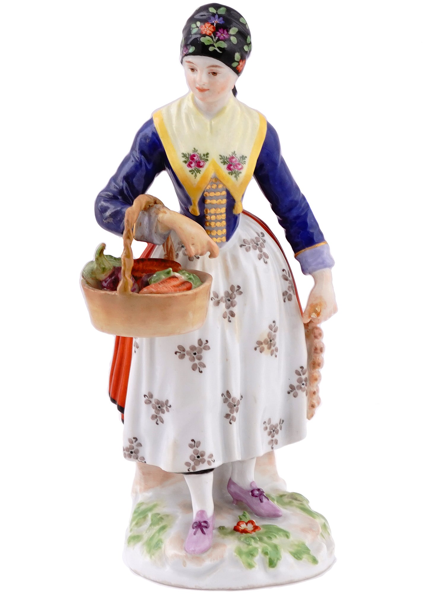A MEISSEN PORCELAIN FIGURINE OF A DANISH FARMER: A Meissen figurine of a young Danish woman with a vegetable basket. Dressed in traditional garb and a head wrap with a basket in right hand, standing atop a round base. Underglaze mark of blue crossed