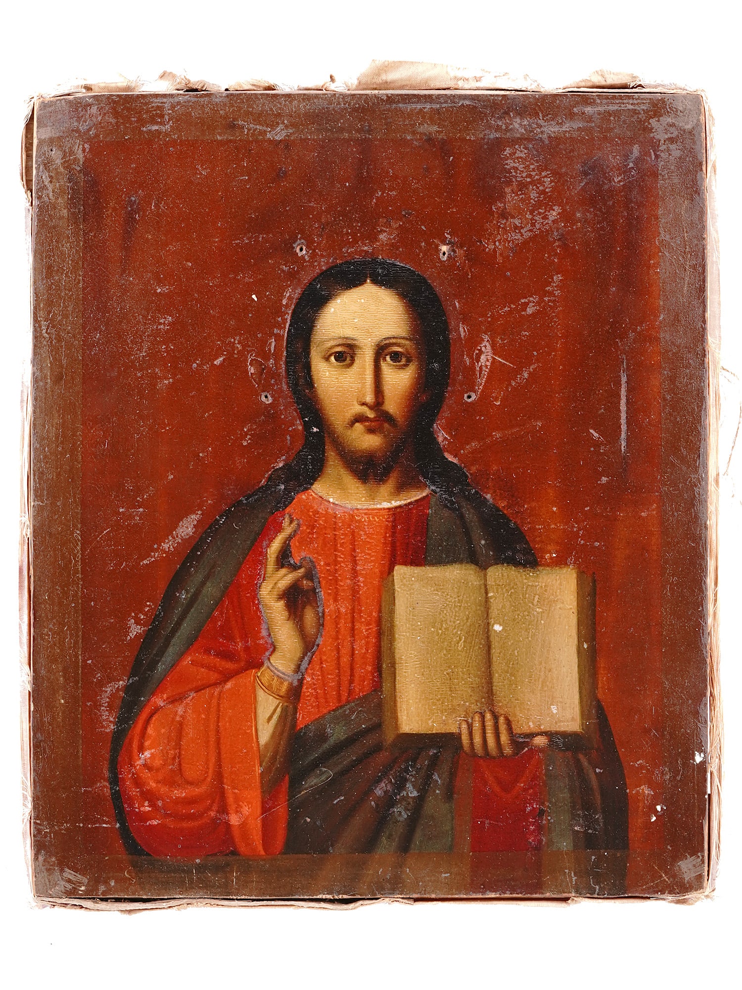 A RUSSIAN ICON TEMPERA ON WOOD OF CHRIST THE PANTOCRATOR: Icon of Christ Pantocrator hand painted in tempera on wood. The piece features Christ blessing with one hand while holding an open Gospel in the other. Purple lining on the reverse. Russia, 19th centu