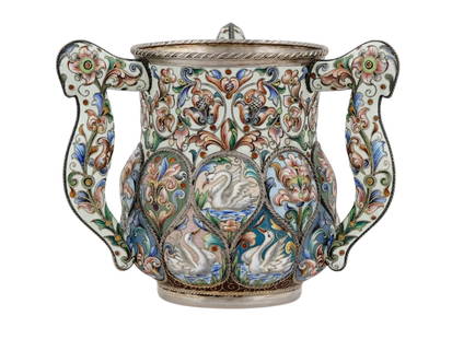 RUSSIAN SILVER AND ENAMEL CUP, RUCKERT, 1899-1908: A SILVER AND CLOISONNÉ ENAMEL THREE-HANDLED CUP (BRATYNA). Feodor Ruckert, Moscow, 1899-1908. The lower body with lobed cartouches depicting swimming swans and brightly colored stylized flowers and f