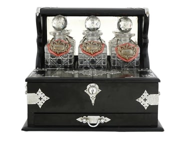 A BLACK EBONY VICTORIAN CASED THREE DECANTER TANTALUS