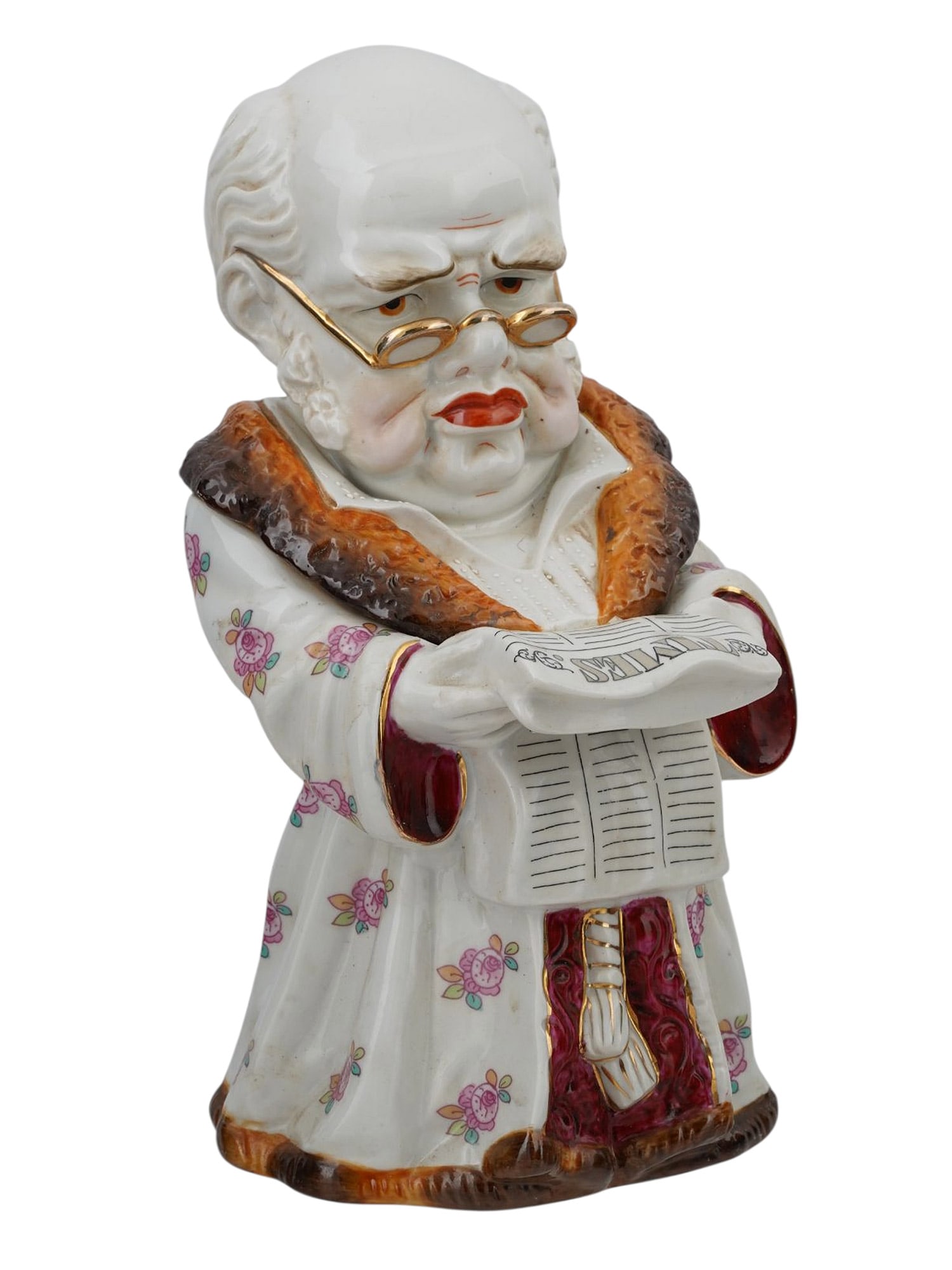 A CONTINENTAL PORCELAIN TOBACCO JAR OF A MAN READING THE TIMES, CA. 1900.: A whimsical and finely painted porcelain figural tobacco jar, depicting a rotund, elderly gentleman in a floral house robe with fur trim, holding a folded newspaper titled THE TIMES in both hands. His