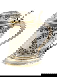 AN ENGRAVED RUSSIAN SILVER LIDDED TANKARD, MOSCOW, 1851: An engraved lidded gilt-silver tankard is of a tapering form, with partially niello-decorated leafy arabesques on a round base. Centered on either side of two cartouches engraved with "1854" and "Mosc