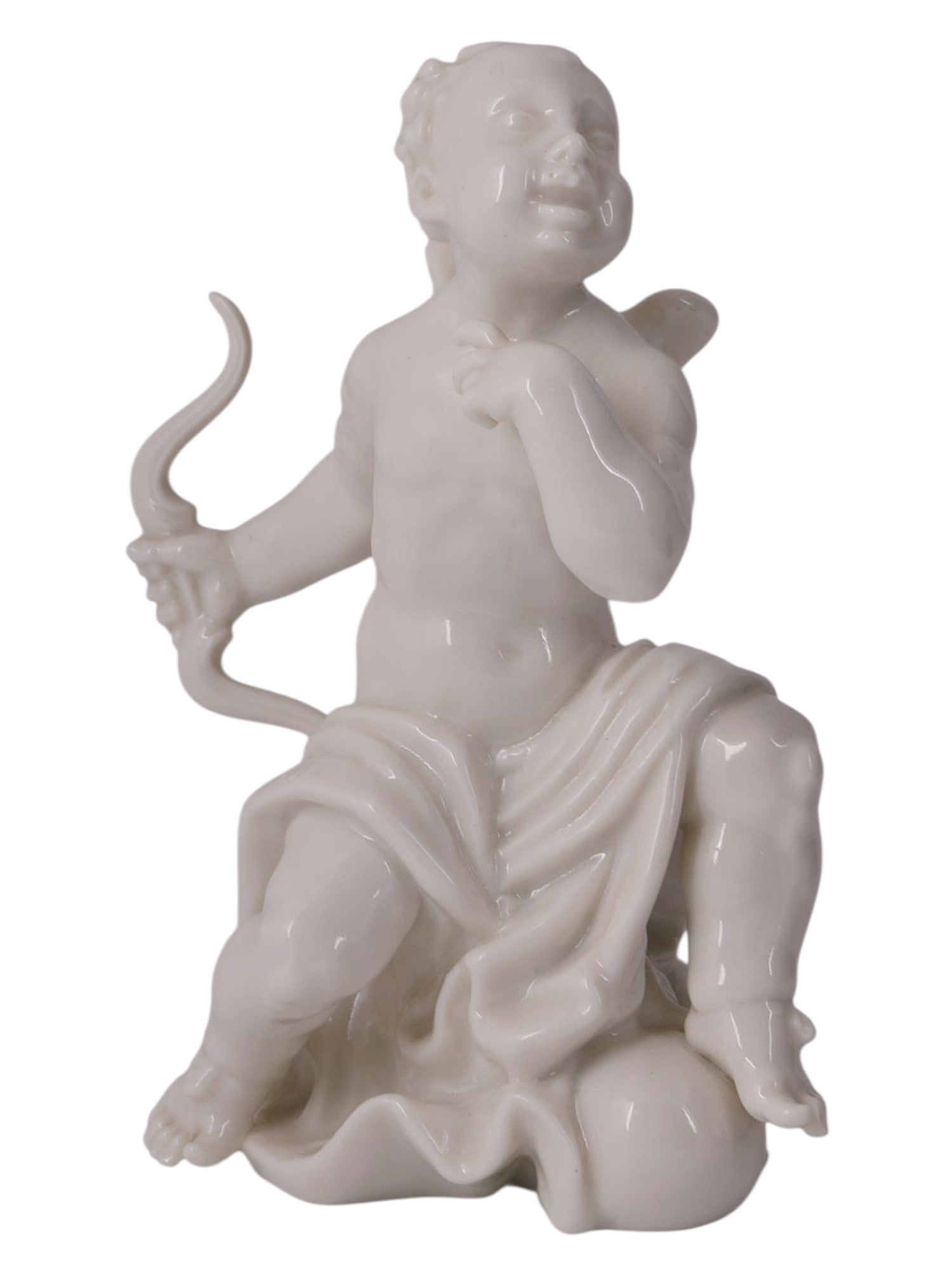 A MEISSEN WHITE PORCELAIN FIGURE OF A SEATED PUTTO WITH BOW, GERMANY, LATE 19TH TO EARLY 20TH: White-glazed porcelain figure depicting a chubby winged putto seated upon a stylized mound, modeled nude with a draped cloth around the hips and holding a curved bow in his left hand. The figure is re