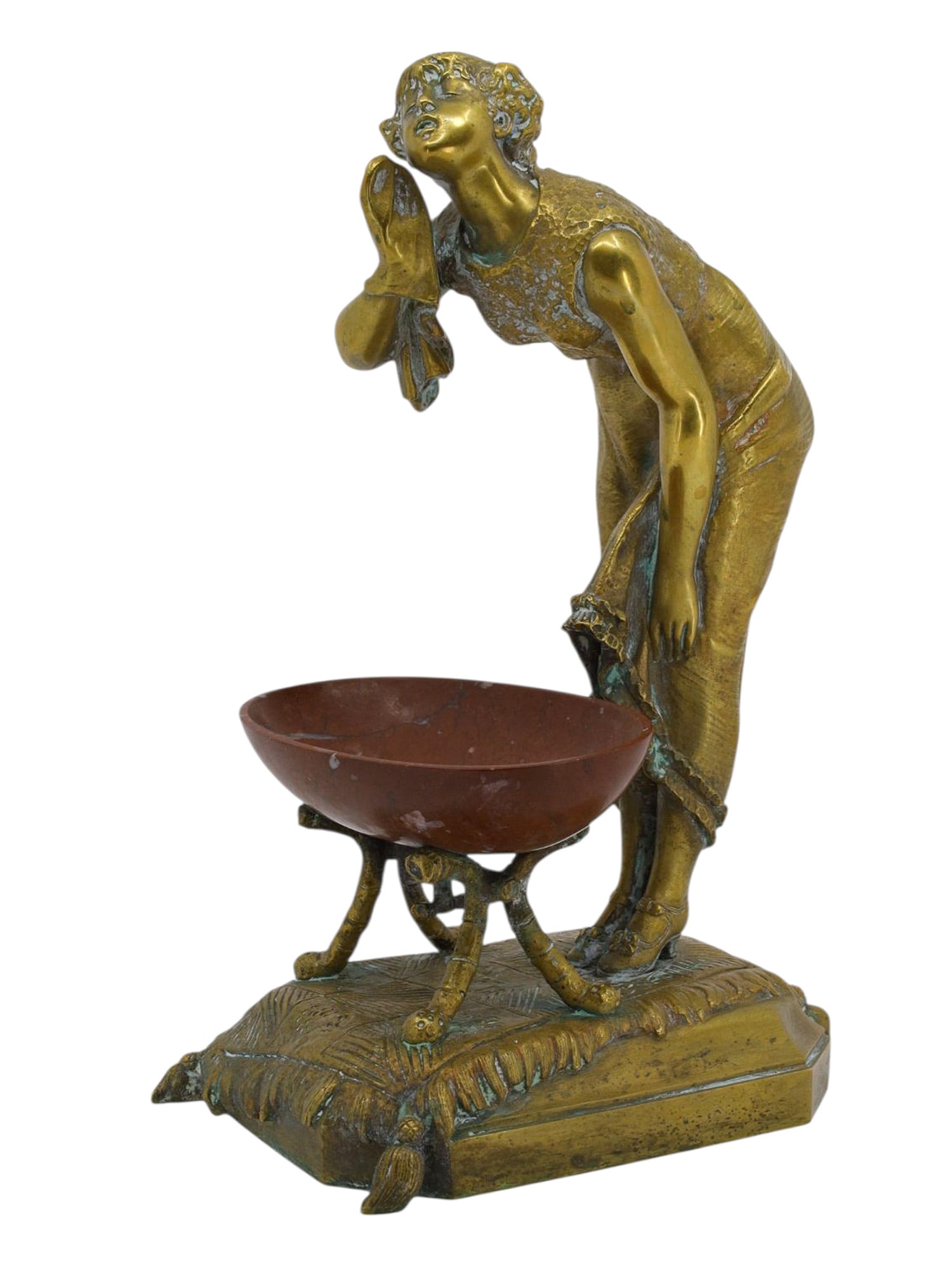 A BRONZE FIGURE OF A LADY ON A CARPET WITH RED MARBLE BOWL, CONTINENTAL, LATE 19TH–EARLY 20TH: A charming gilt-bronze decorative figure depicting a young woman leaning gracefully forward, one hand raised to her cheek and the other holding her skirt, posed in front of an oval bowl carved of deep