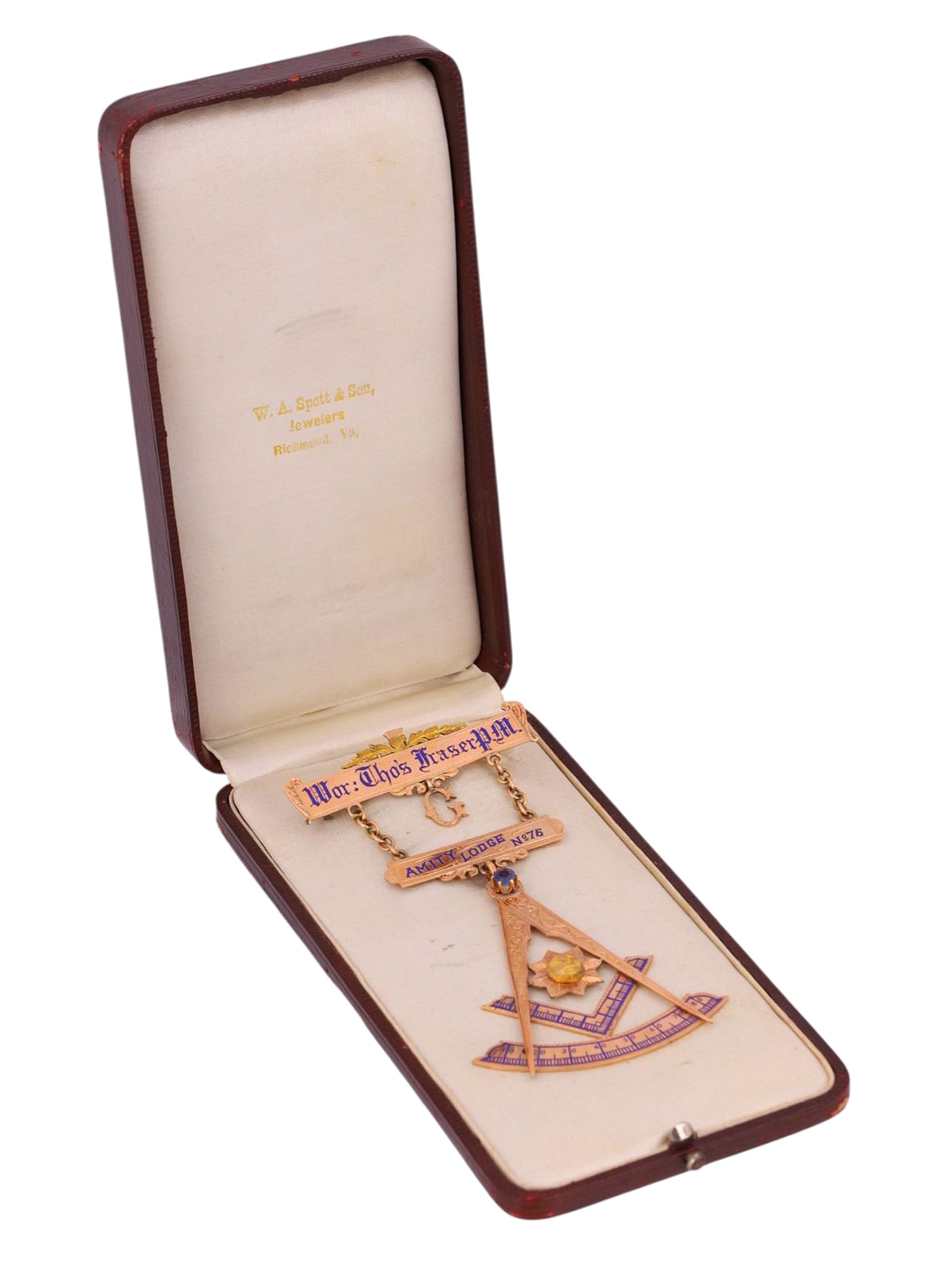 A CASED 1899 FREEMASONS AMITY LODGE NO. 76 HANGING BADGE: Three-part hanging badge. The lower part is the Freemasonry symbol, which is looped and suspended from a bar marked AMITY LODGE NO. 76 on the front. The bar, in turn, is double looped and suspended by