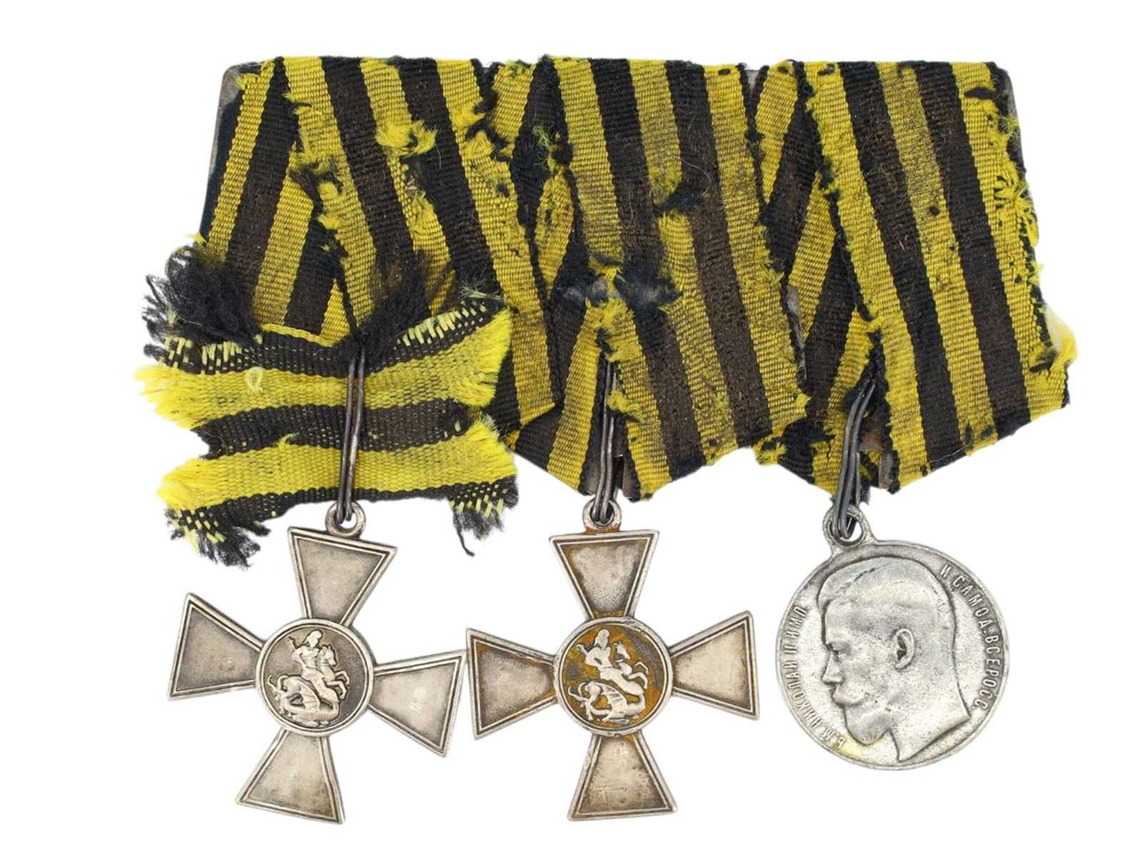 A GROUP OF THREE IMPERIAL RUSSIAN MILITARY AWARDS MOUNTED TOGETHER ON A STEEL BAR: A group of three Imperial Russian military medals mounted on a suspension device with the original black and yellow St. George’s ribbons. Cross of St. George, 4th Class (left), silver cross, inscrib