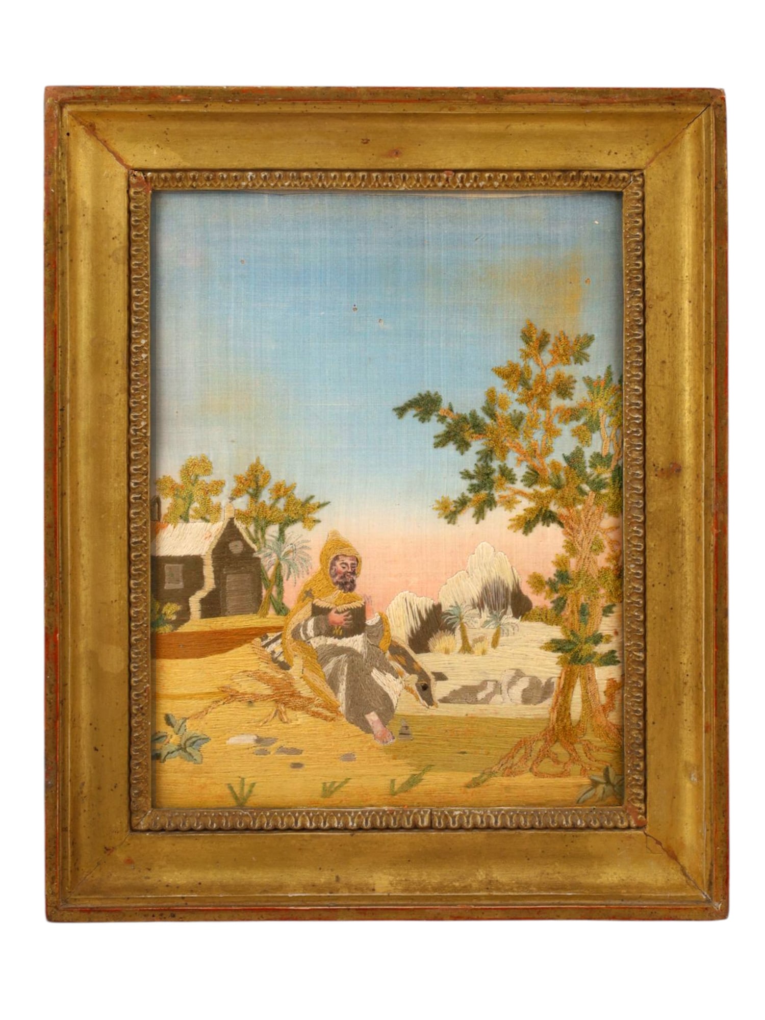 AN ENGLISH RELIGIOUS NEEDLEWORK PICTURE, CIRCA 1810: Worked in polychrome silk threads on a silk ground, depicting a robed hermit saint seated beneath a tree in a pastoral setting, a rustic hut to the left and distant mountains in the background. The fi