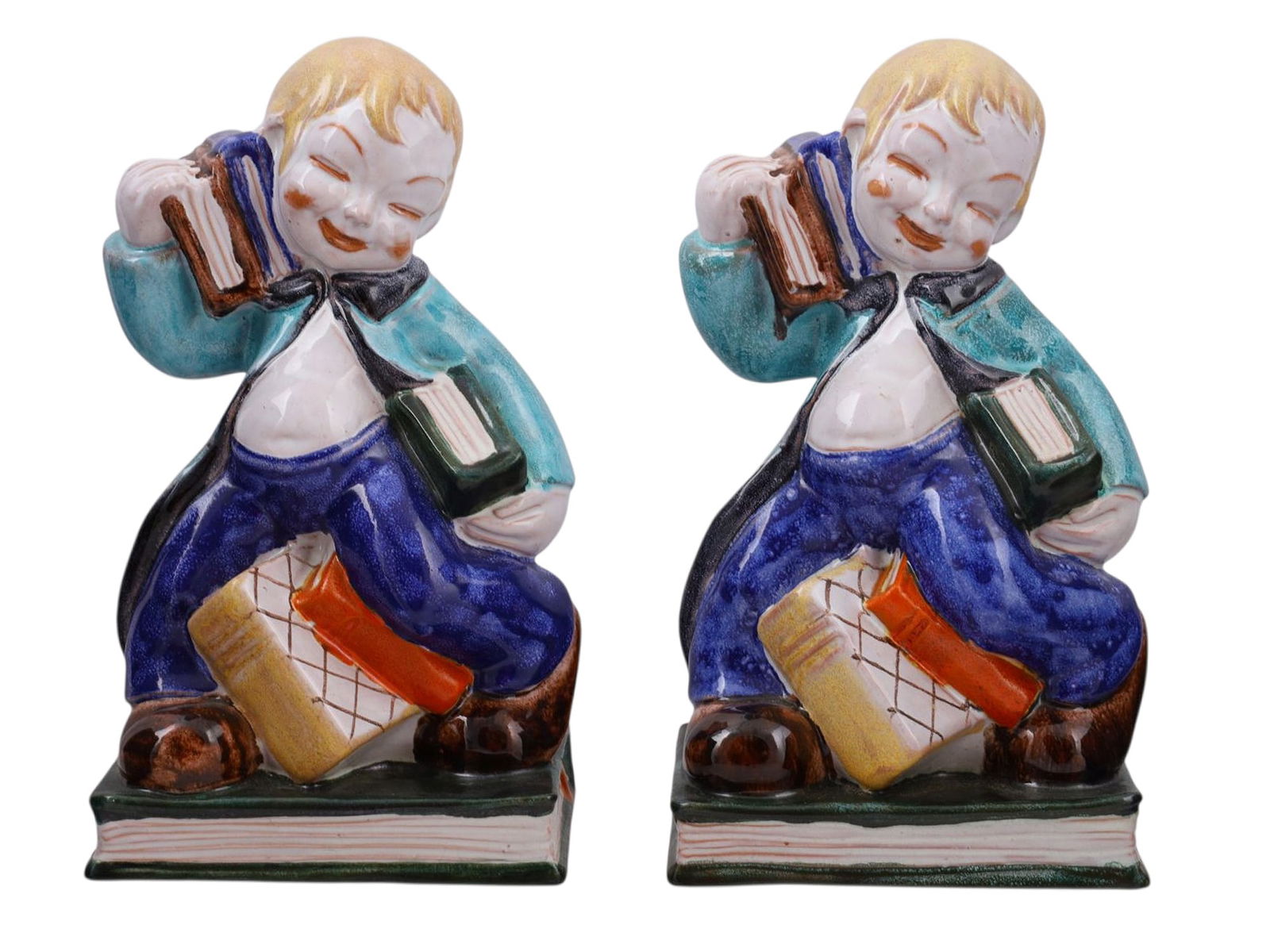 A PAIR OF VIENNESE ANZENGRUBER PORCELAIN FIGURAL BOOKENDS, C. 1920S: A pair of porcelain bookends made by Anzengruber Keramik of Vienna, Austria, appearing as two playful young boys running with bundles of books in their arms, some falling to the ground as they go. The