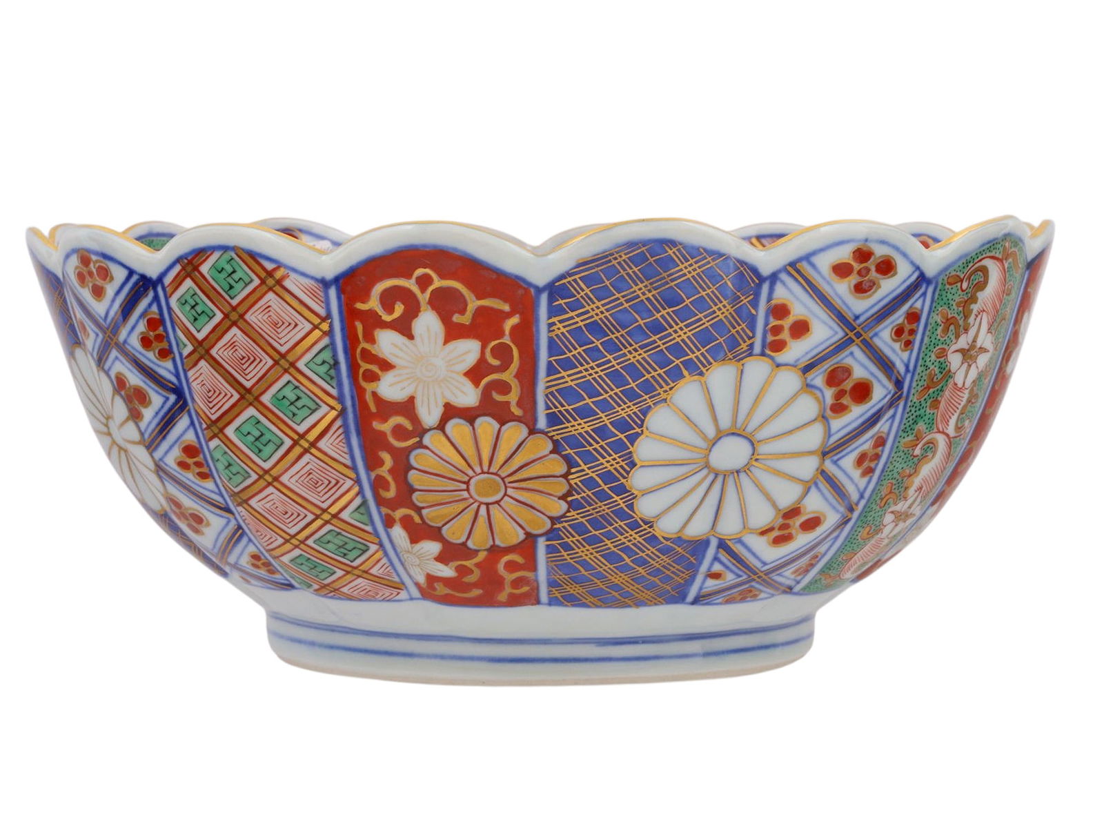 AN IMARI PORCELAIN BOWL, MEIJI PERIOD, LATE 19TH CENTURY: A scalloped-rim Imari porcelain bowl, richly decorated in underglaze cobalt blue with overglaze iron-red, green enamels, and gilt. The exterior is arranged in alternating panels featuring stylized chr