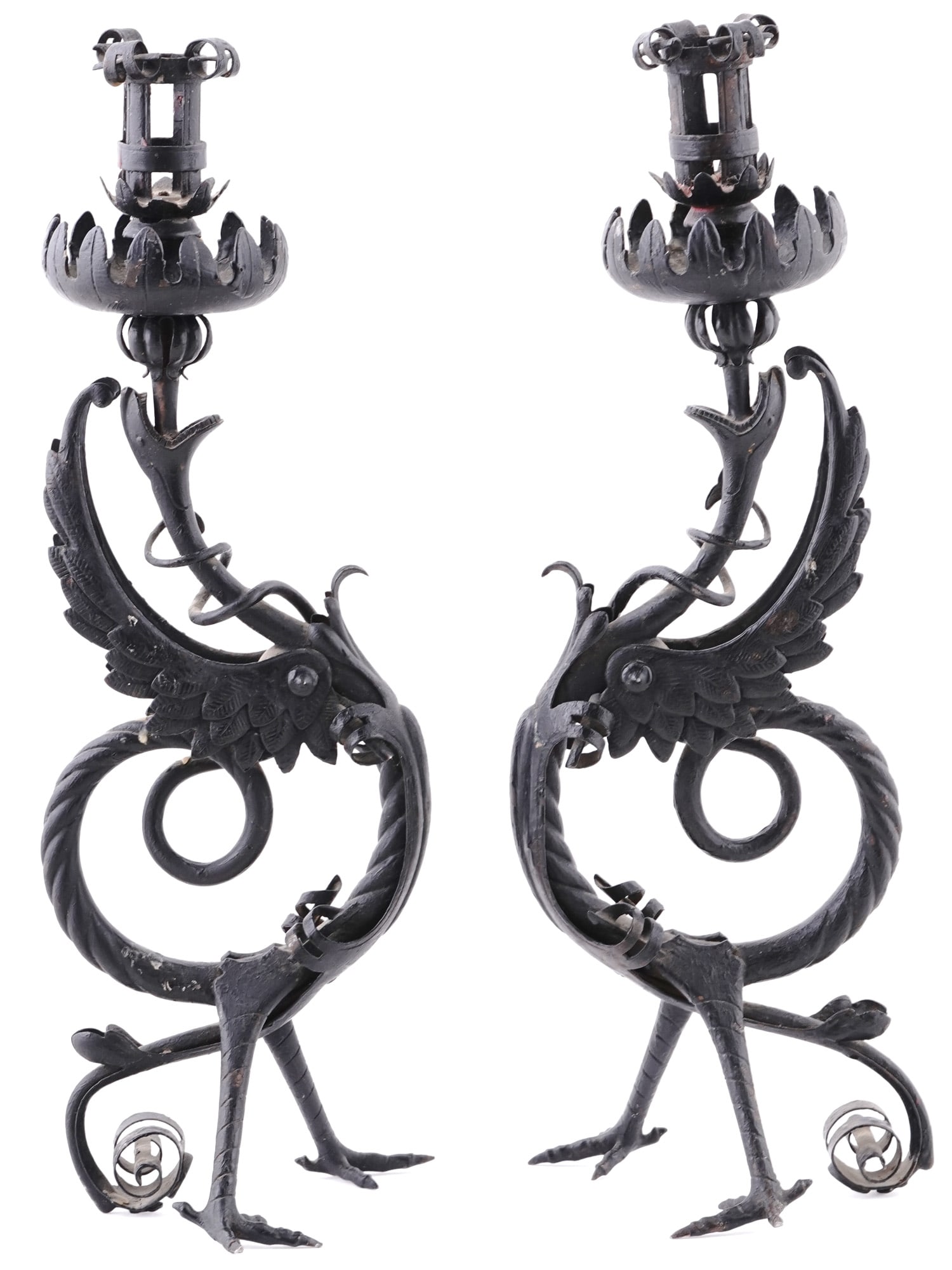 A RENAISSANCE WROUGHT IRON BESTIAL PAIR OF CANDLESTICKS: A late 19th century Renaissance revival pair of candle holders with figural design. Black painted wrought iron griffins candlesticks, standing on foot and tails, curved body with bird-like wings, long