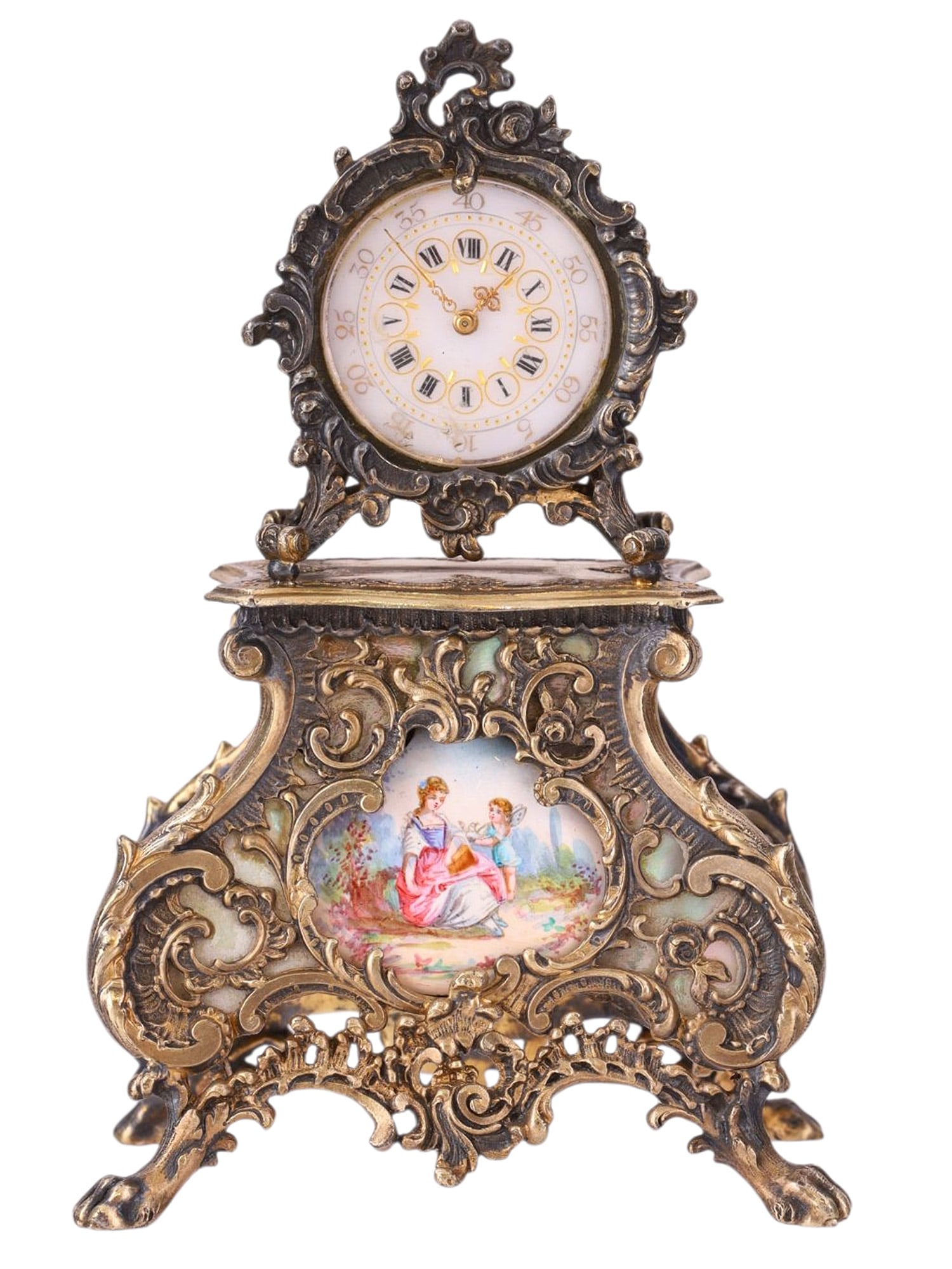 AN AUSTRIAN OPEN WORK SILVER AND ENAMEL CLOCK, 19TH CENTURY: A finely cast and chased Austrian miniature table clock, the case formed in high-relief openwork silver with rococo revival scrolls, shellwork, and foliate ornament, raised on four scrolling feet. The
