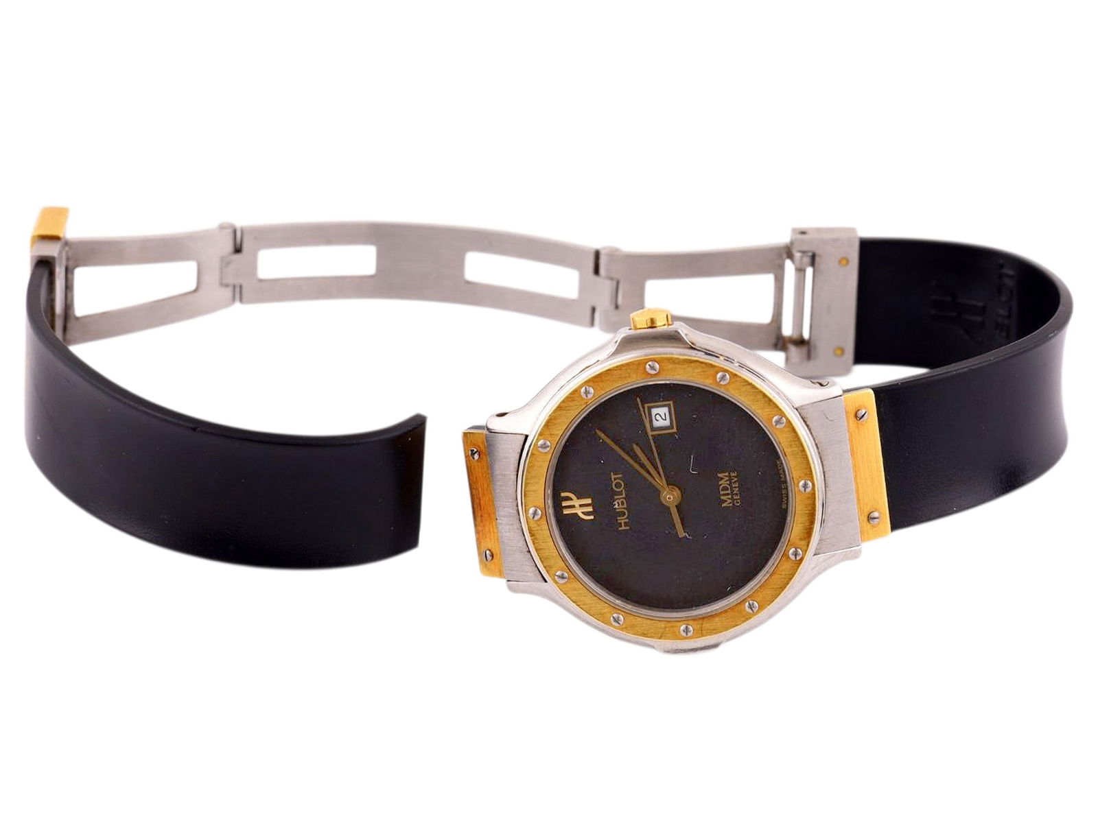 A LADY’S HUBLOT MDM GENEVE WRISTWATCH WITH GOLD BEZEL AND GOLD BUCKLE, SWISS, CIRCA 1990: The wristwatch features a round stainless steel case with integrated lugs, fitted with a yellow gold bezel secured by exposed screws, enclosing a black dial signed Hublot, with applied gold baton hour