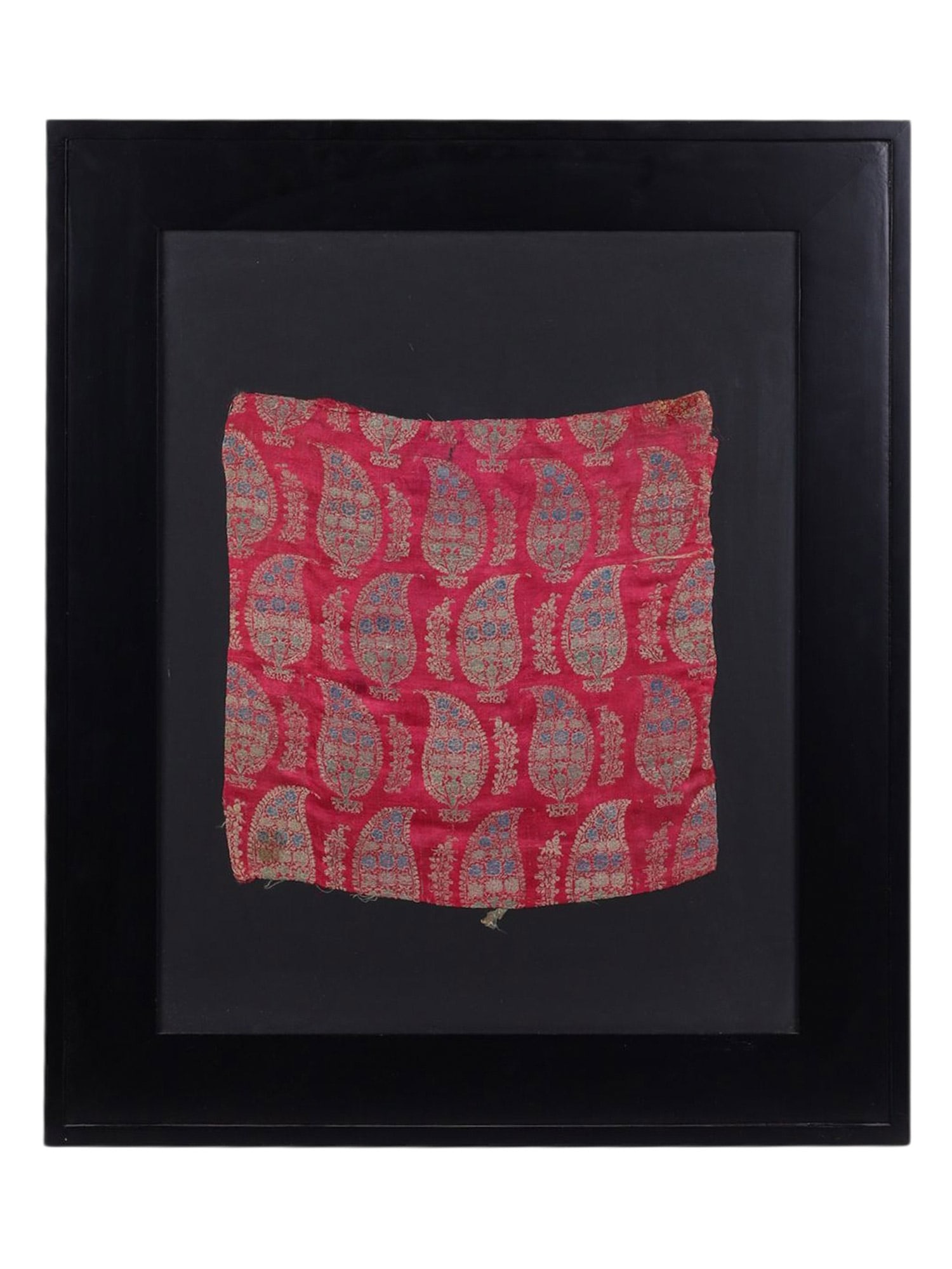 A FRAMED SECTION OF PERSIAN TEXTILE, C. 19TH CENTURY: A decorative fragment of Persian textile mounted and framed for display, woven or block-printed in a repeating boteh or paisley pattern on a rich red ground. The design features stylized vegetal motif