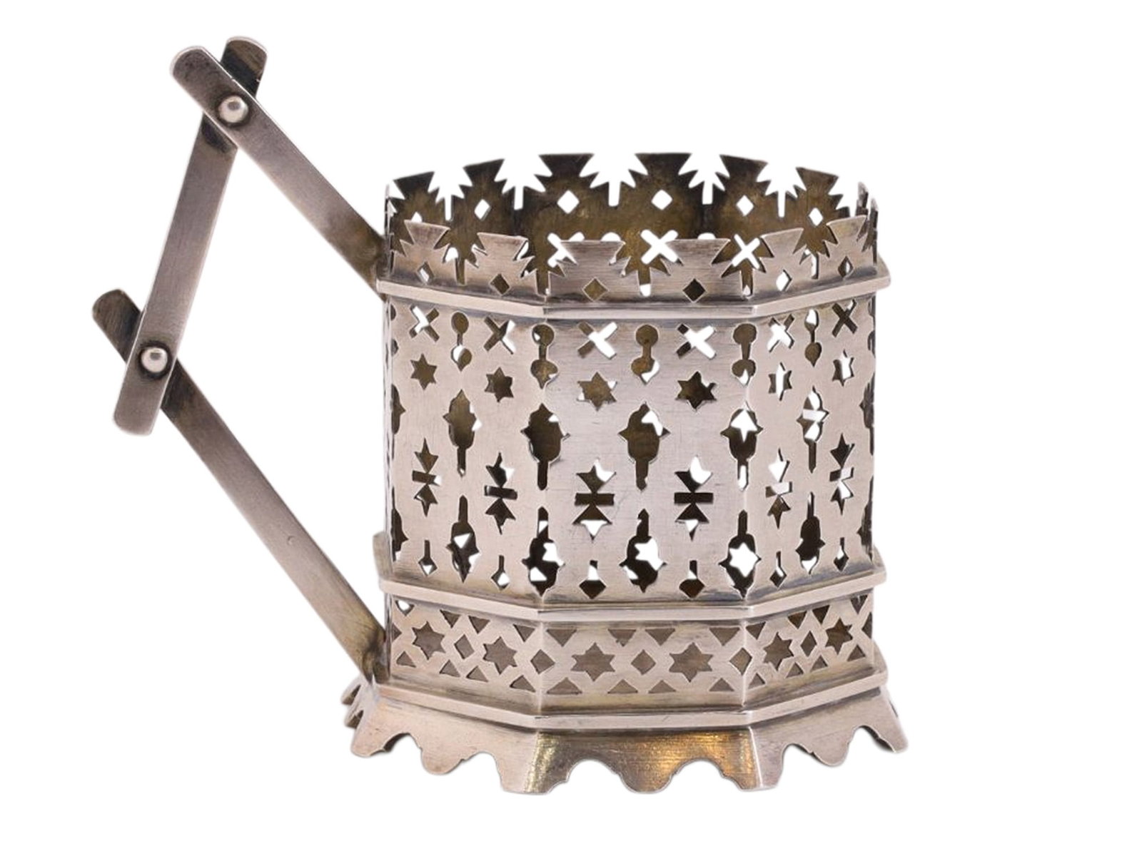 AN UNUSUAL RUSSIAN SILVER TEAGLASS HOLDER IN OPENWORK NEO-RUSSIAN STYLE: Of faceted, openwork construction, the body executed in the Neo-Russian taste, imitating forms and motifs of traditional peasant wooden utensils. The pierced sides and shaped rim create a lively silho