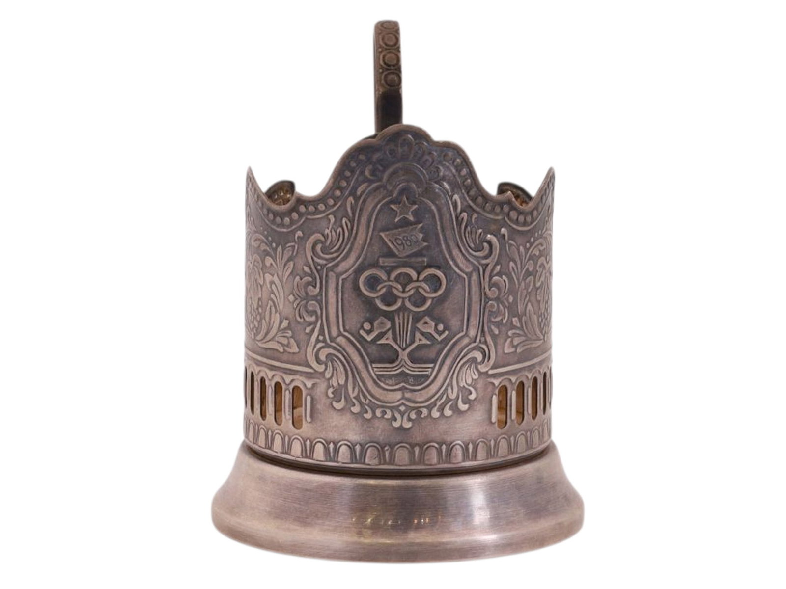 A SOVIET 1980 OLYMPICS COMMEMORATIVE TEAGLASS HOLDER: A cylindrical nickel silver podstakannik with floral ornament and the emblem of the Moscow Olympic Games of 1980 within a central medallion.On the interior of the base are marks including a "capercail