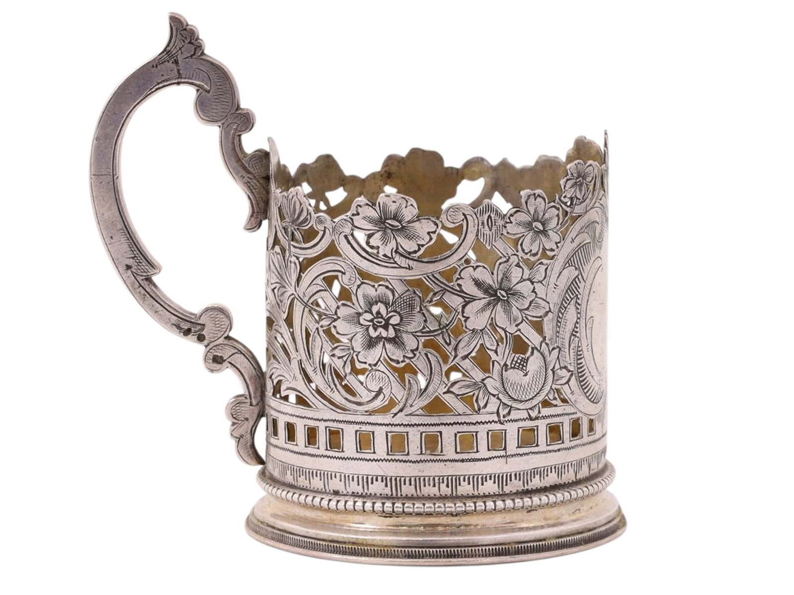 A RUSSIAN OPENWORK SILVER TEAGLASS HOLDER WITH FLORAL DECORATION: A Russian silver podstakannik (tea glass holder) with intricate openwork and engraved floral patterning across its entire circumference, space for a monogram left clear at the front.Hallmarks: kokoshn