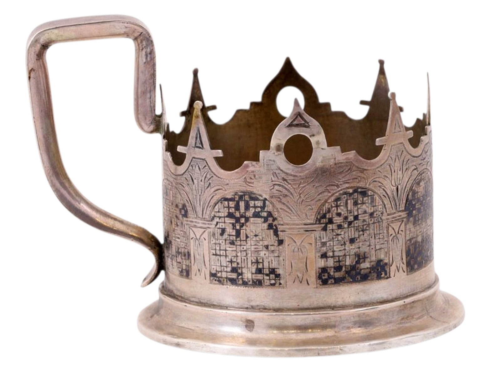 A RUSSIAN SILVER AND NIELLO TEAGLASS HOLDER IN NEO-RUSSIAN STYLE, GRIGORY IVANOV WORKSHOP, 1866: A cylindrical teaglass holder featuring a cut-out and engraved design with black niello, imitating the chambers of a boyar’s tower.The lower rim and the bottom bear the following hallmarks: assa