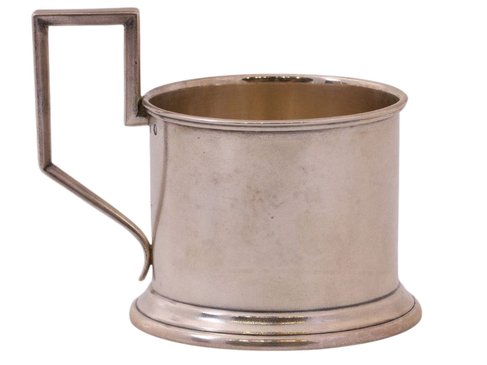 A RUSSIAN SILVER TEA GLASS HOLDER, MOSCOW, 1889: A cylindrical tea glass holder with a rectangular handle, featuring a simple, unadorned design.Cyrillic hallmarks are present on the upper rim, the handle, and the base: the assayer’s mark is pa