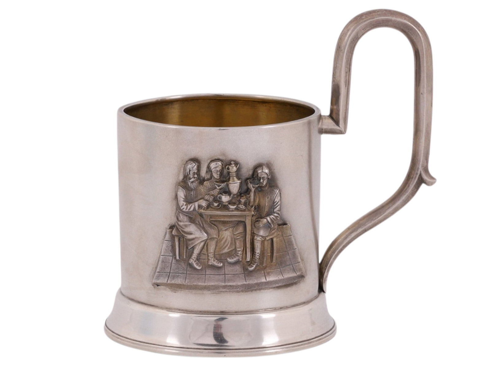 A RUSSIAN SILVER TEAGLASS HOLDER WITH GENRE SCENE, LATE 19TH CENTURY: Of cylindrical form on a stepped circular foot, the plain body is applied with a finely cast and chased relief panel depicting three figures seated at a table in an interior setting, gathered around a