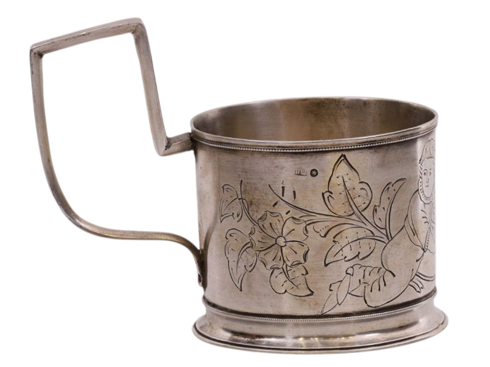 A RUSSIAN SILVER COMMEMORATIVE TEAGLASS HOLDER, PRIVATE WORKSHOP OF PAVEL SHUTENKOV, MOSCOW, 1880S: Of cylindrical form with a rectangular handle on a ring foot, the body engraved on one side with a floral composition incorporating a figure of a boy holding a scroll. The scroll bears engraved initia
