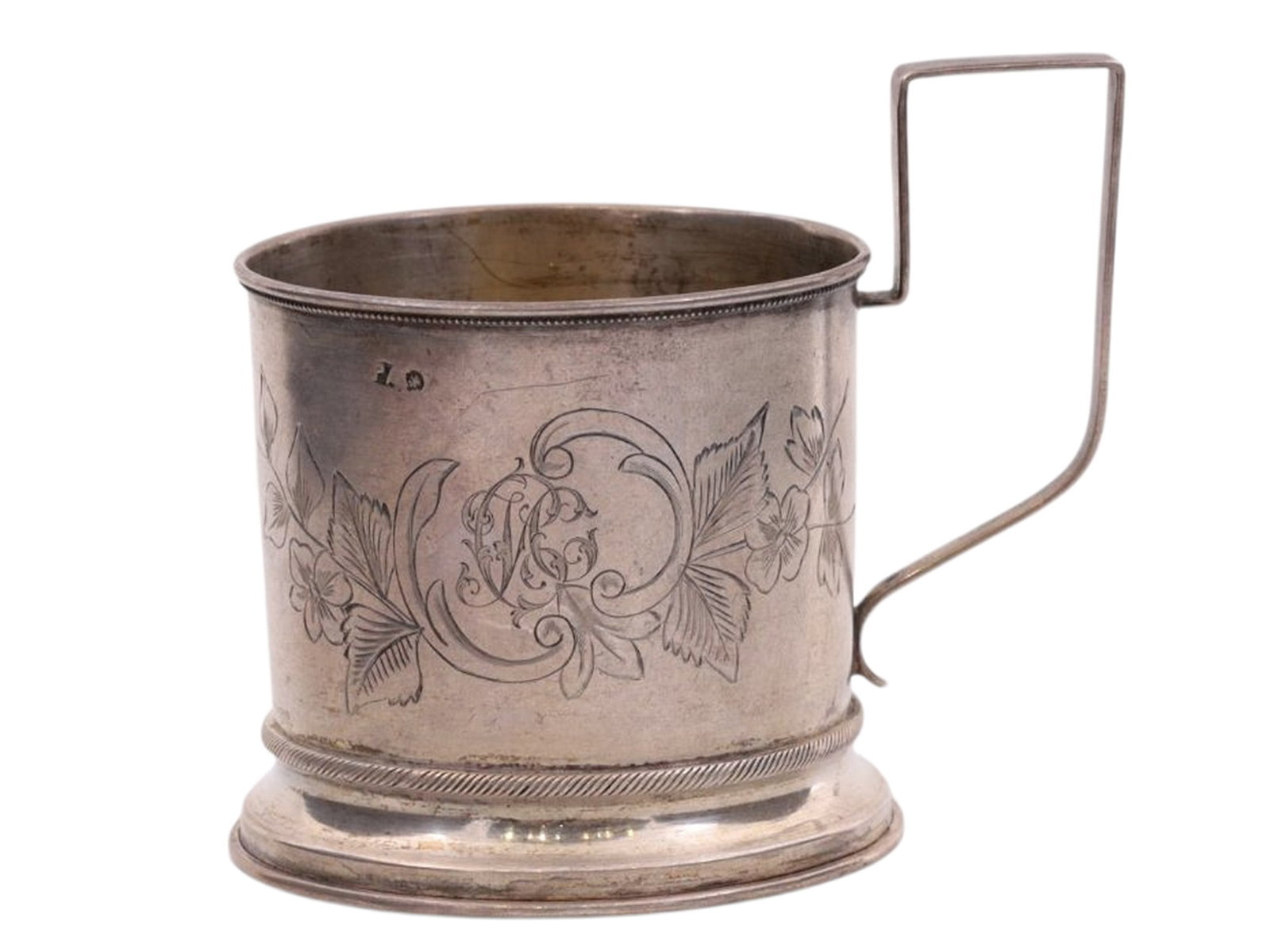 A RUSSIAN SILVER TEAGLASS HOLDER, PRIVATE WORKSHOP OF ROMAN ARISTARKHOV, MOSCOW, 1890S: Of cylindrical form with a rectangular handle on a ring foot, the upper and lower borders decorated with geometric guilloche bands. One side engraved with a floral composition forming an asymmetrical 