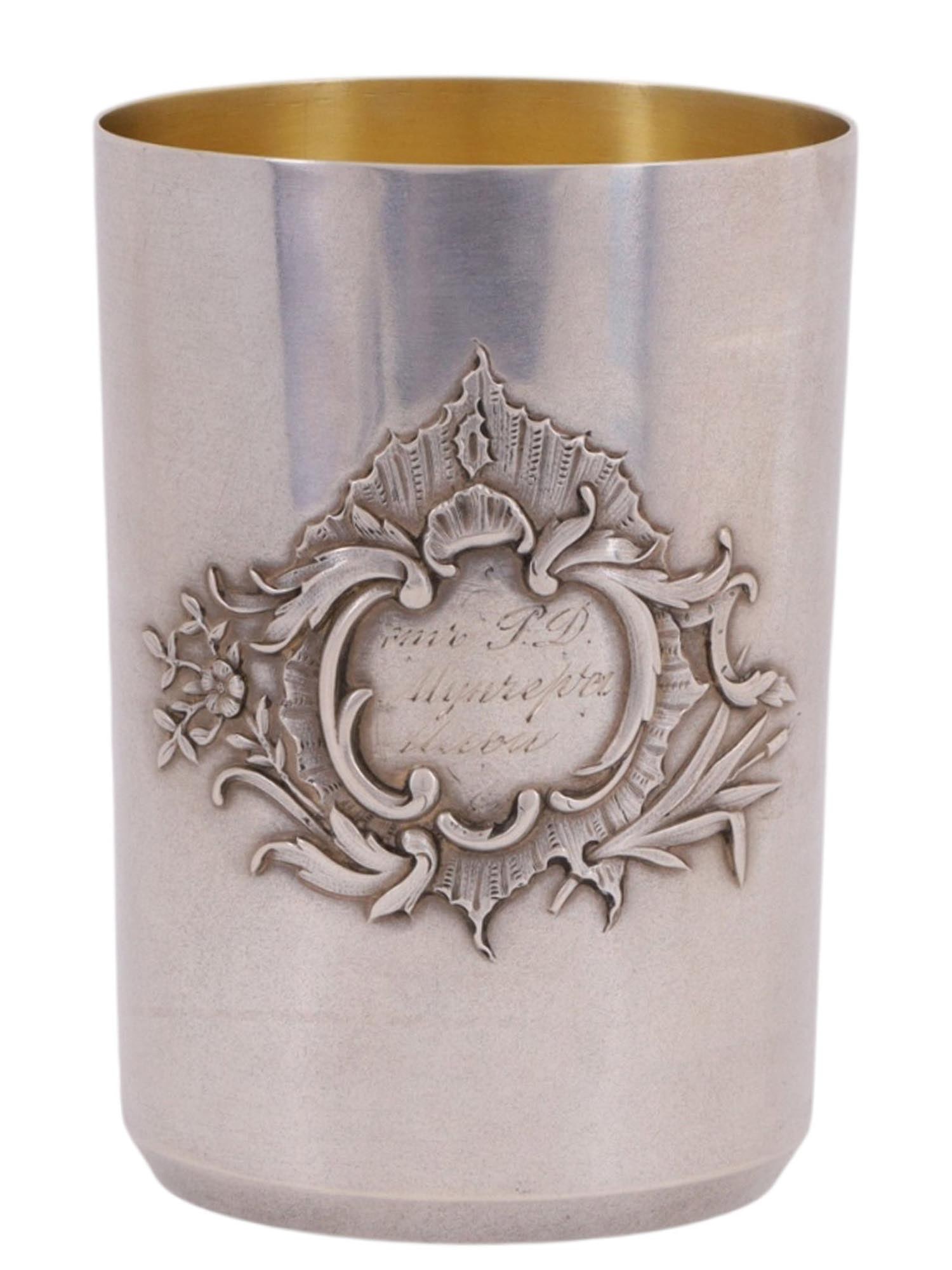 A LARGE RUSSIAN SILVER GLASS BY NEMIROV-KOLODKIN: A conical-form beaker, decorated on one side with a cartouche featuring a scrolling vegetal monogram design and an engraved Cyrillic inscription: "From R.D. // Muncherova [illegible] // Ilya."The base