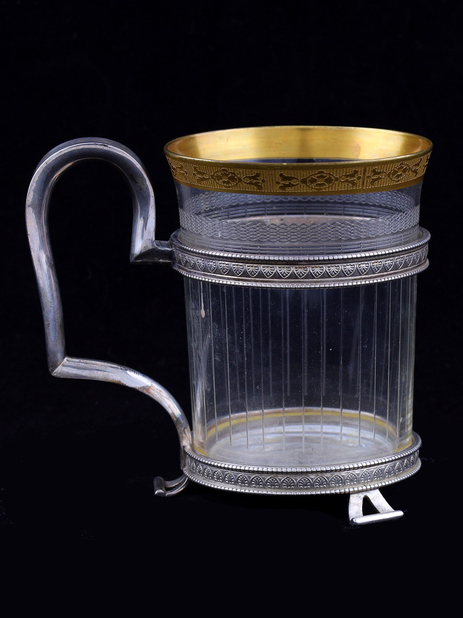 A RUSSIAN SILVER OPENWORK TEAGLASS HOLDER, WORKSHOP OF VASILY KARGIN, ST. PETERSBURG, RUSSIA, LATE: The body is composed of upper and lower circular bands joined by supports and a rectangular handle, raised on three curved feet. The bands are decorated with a guilloche pattern of palmettes, reflecti