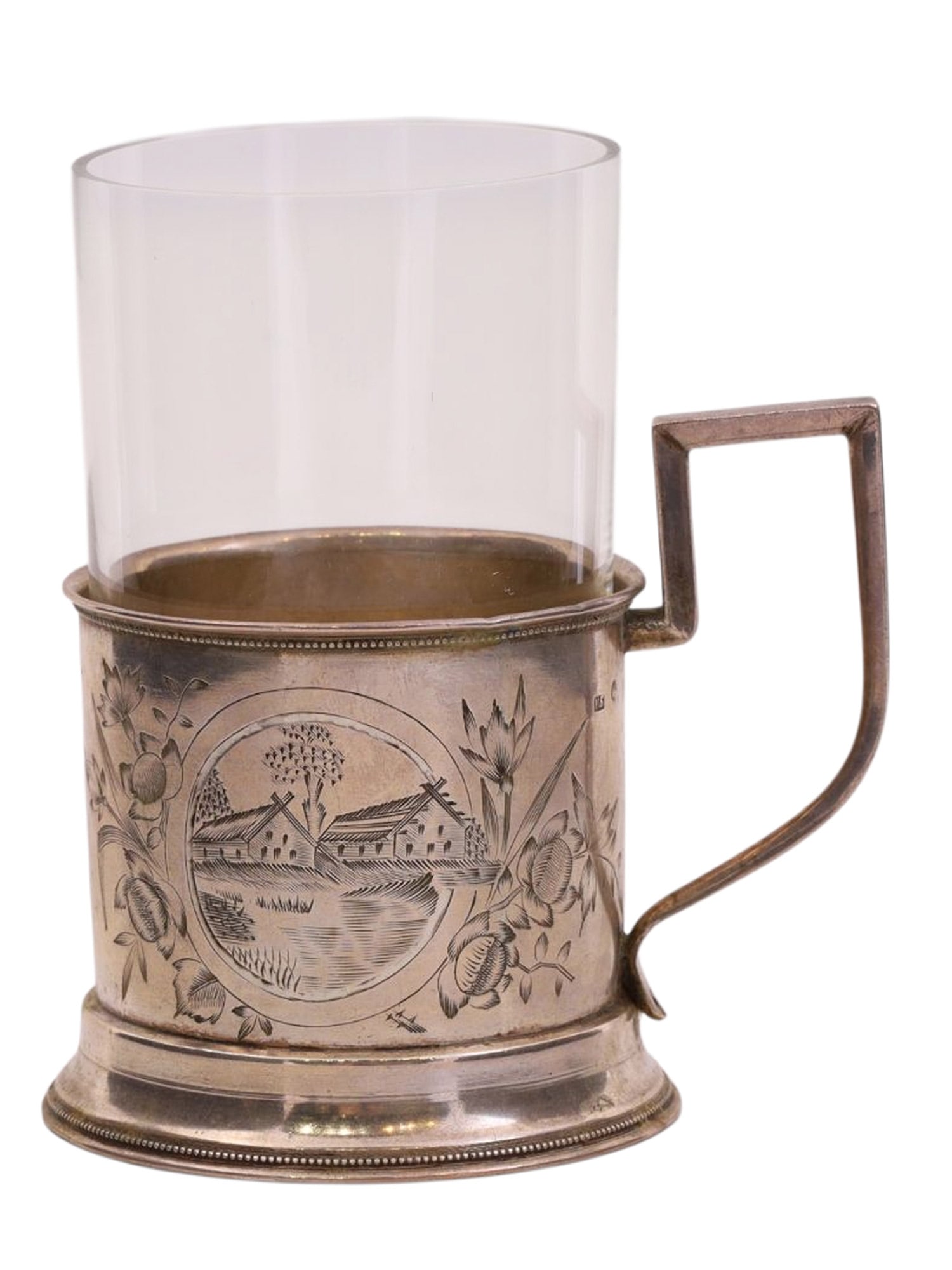 A RUSSIAN SILVER TEAGLASS HOLDER WITH VILLAGE SCENE, IVAN BUTUZOV WORKSHOP, 19TH / 20TH CEN.: A cylindrical tea glass holder with a rectangular handle, resting on a wide ring-shaped base, is decorated on one side with a floral pattern forming a central medallion depicting a Russian village. Th