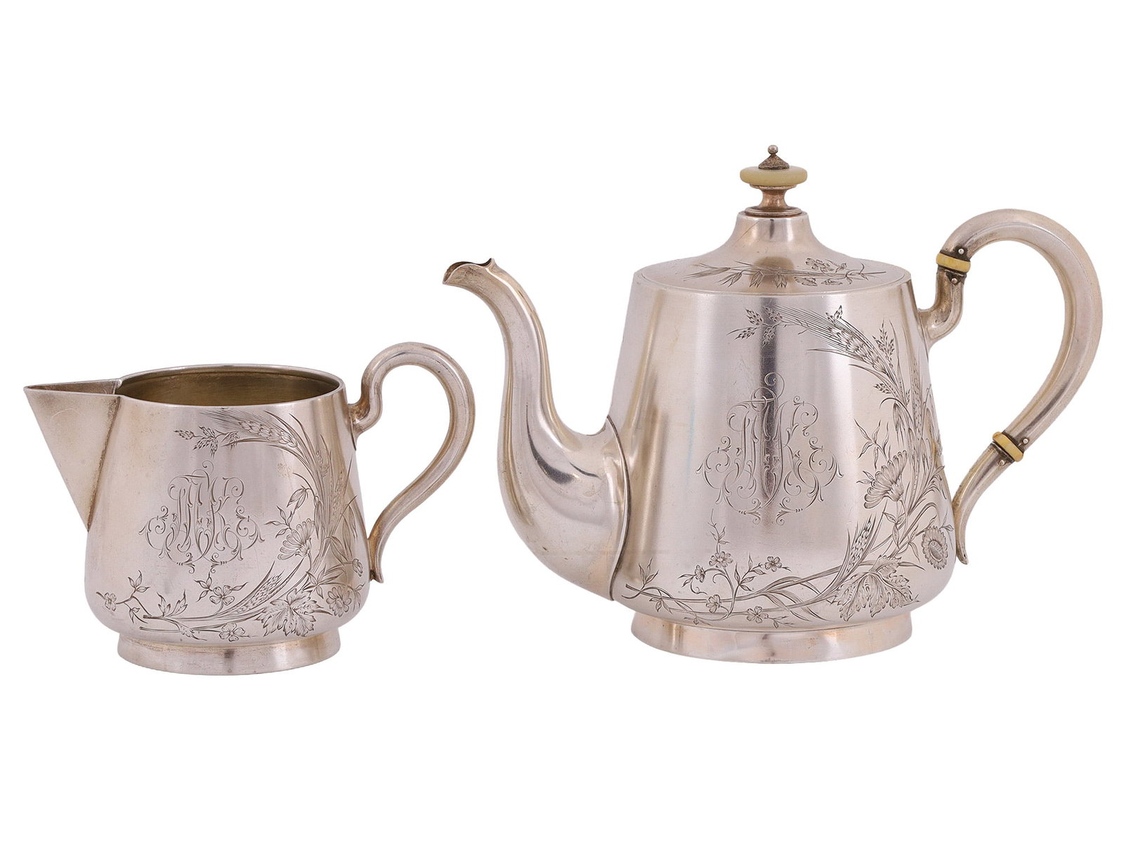 A RUSSIAN SILVER COFFEE POT AND MATCHING CREAMER, ST. PETERSBURG, LATE 19TH TO EARLY 20TH CENTURY: Comprising a coffee pot and matching creamer, each of baluster form on a stepped circular foot, the bodies finely engraved with flowing floral and foliate ornament in the Art Nouveau taste, centered w