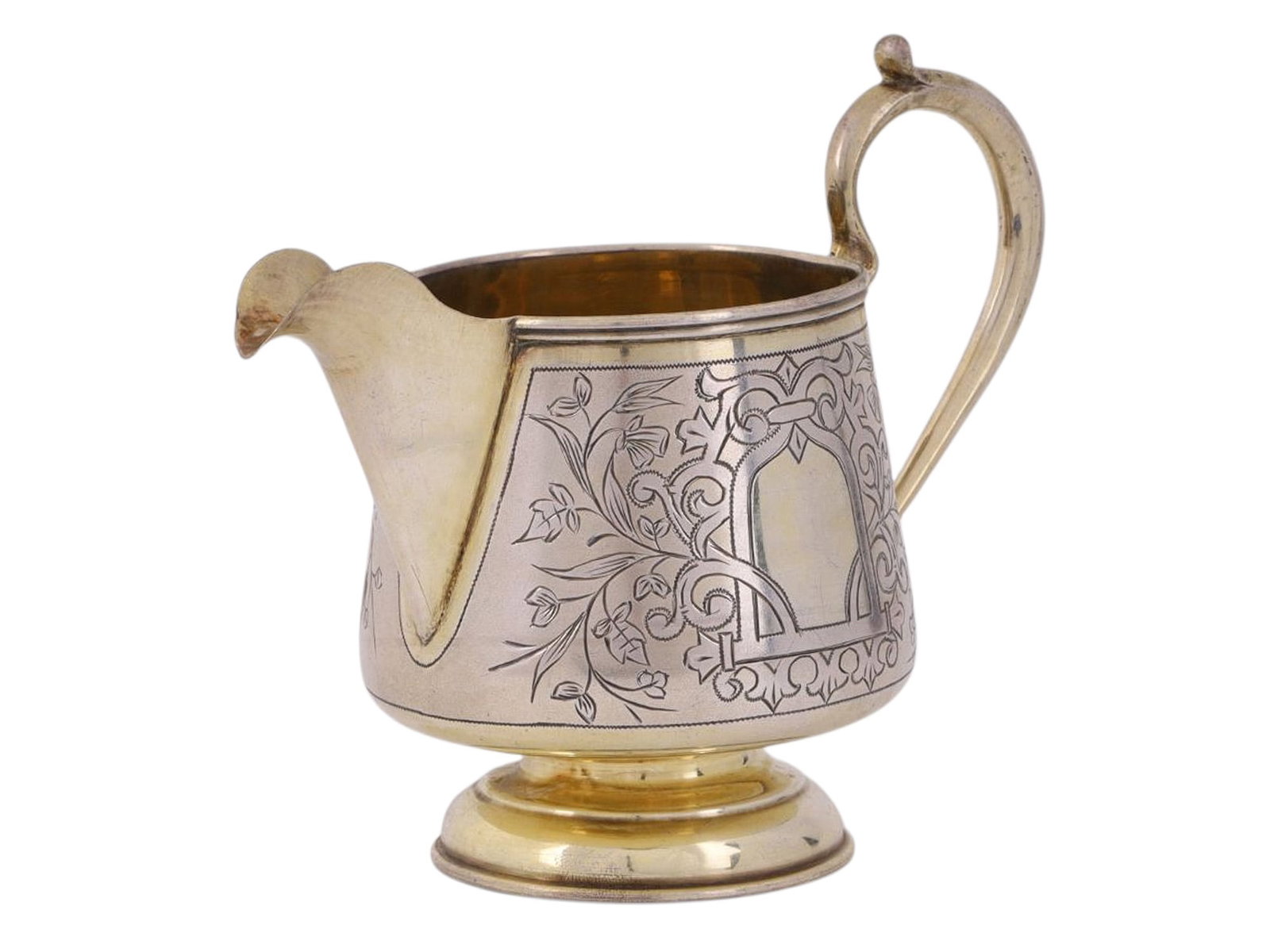 A RUSSIAN PARCEL-GILT SILVER CREAMER IN NEO-RUSSIAN STYLE, WORKSHOP OF MIKHAIL GOLOSHCHAPOV, C.: A cone-shaped creamer on a ring base, with a smooth S-shaped handle; the body is decorated with an asymmetrical geometric-floral pattern that forms a medallion on one side, with gilding inside.There a
