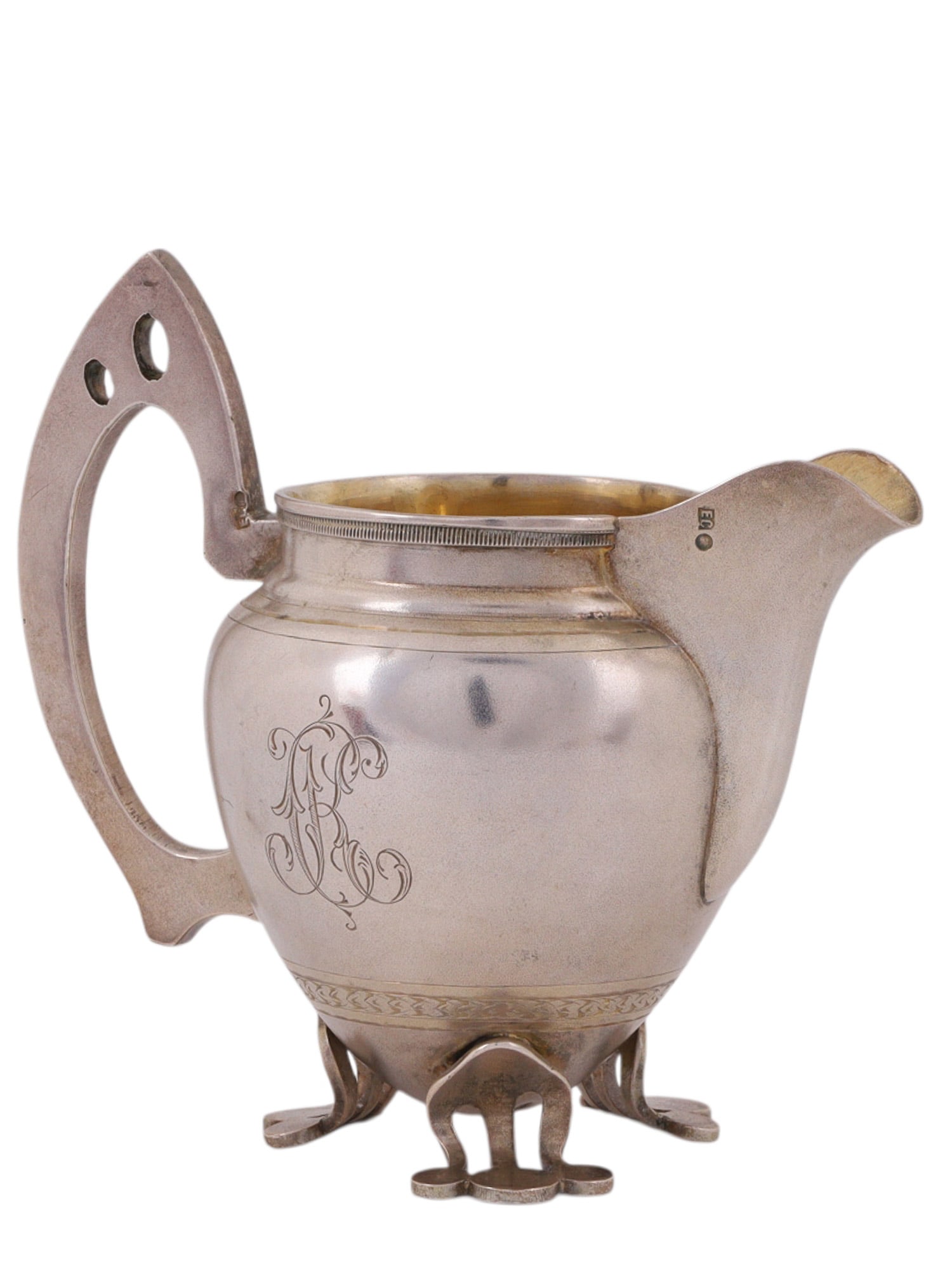 A RUSSIAN PARCEL-GILT SILVER CREAMER IN ART-NOUVEAU STYLE: A creamer jug produced at the end of the 19th century in art-nouveau style, with a stylized handle and its belly engraved with floral and geometric patterns and a large monogram.Hallmarks: 'EC' mark, 