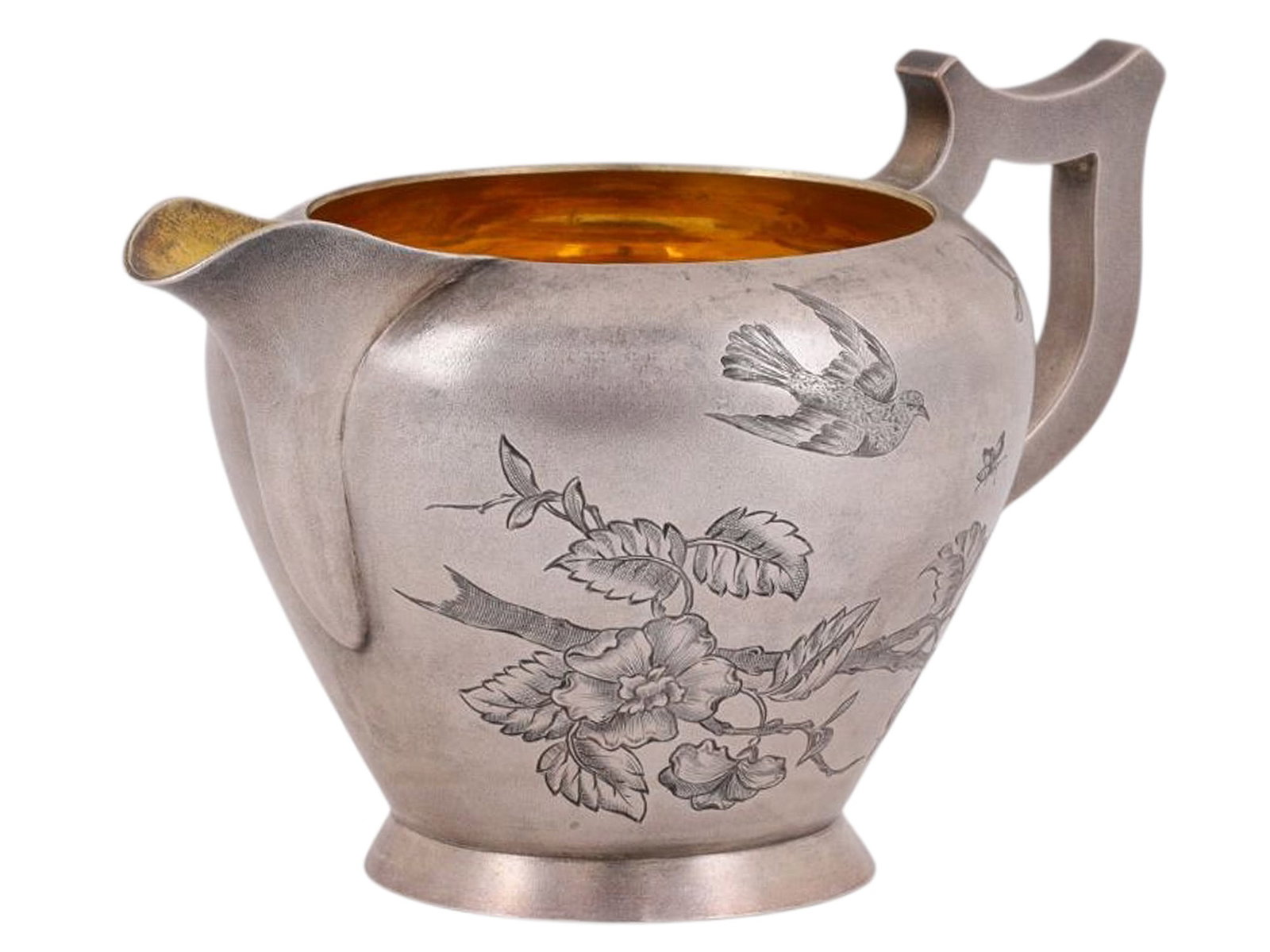 A RUSSIAN PARCEL-GILT SILVER CREAMER WITH DETAILED ENGRAVING, 1894: A Russian parcel-gilt silver creamer with a wide belly which has been beautifully engraved with a scene of a small bird chasing an insect through the air, both passing by a tree branch adorned with bl