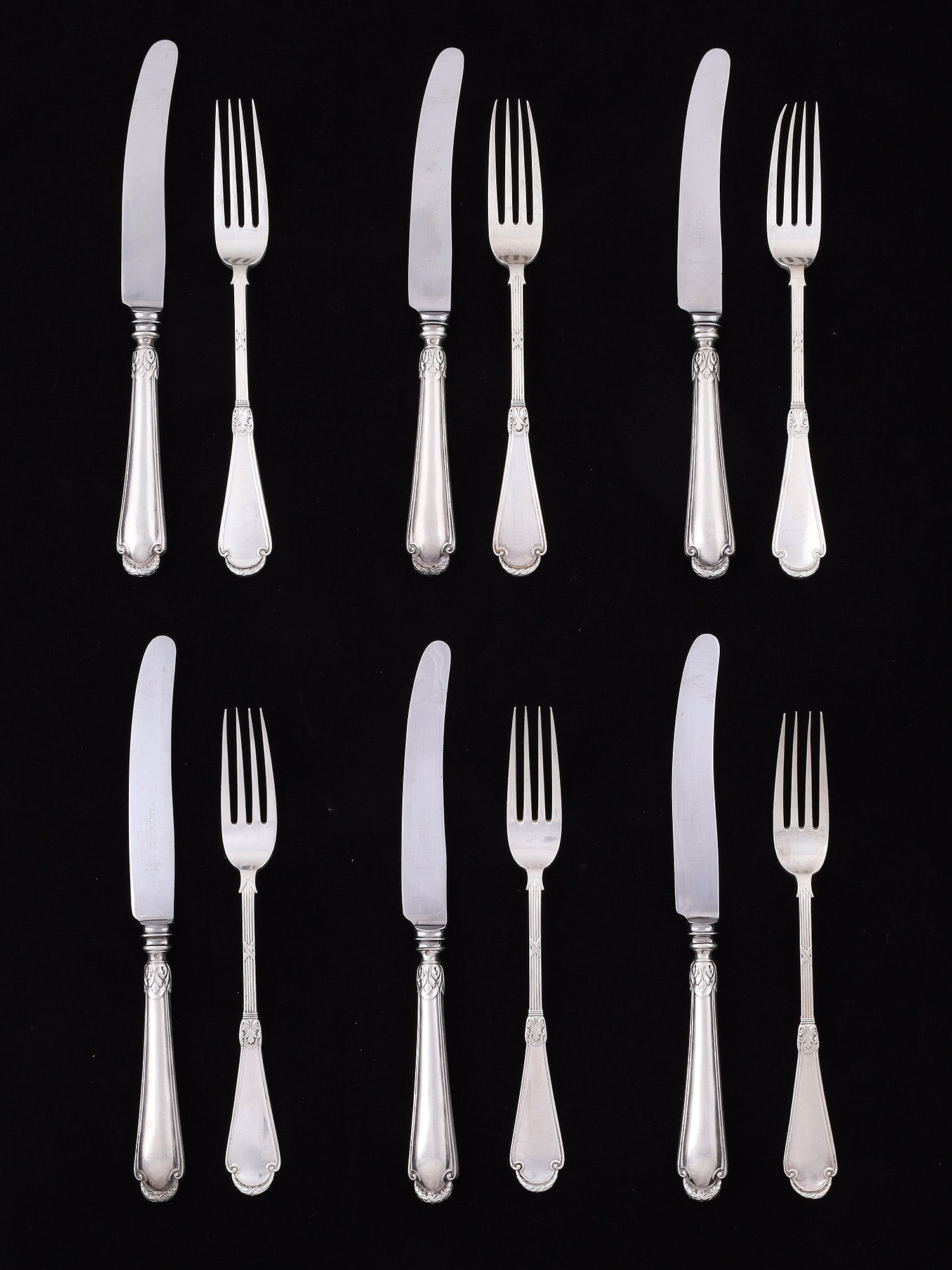A LOT OF TWELVE FABERGÉ SILVER FLATWARE, RUSSIA, CIRCA 1900: Comprising twelve pieces of silver flatware by Fabergé. The lot includes six table forks and six table knives. Each fork has a tapering handle terminating in a rounded terminal with molded scroll
