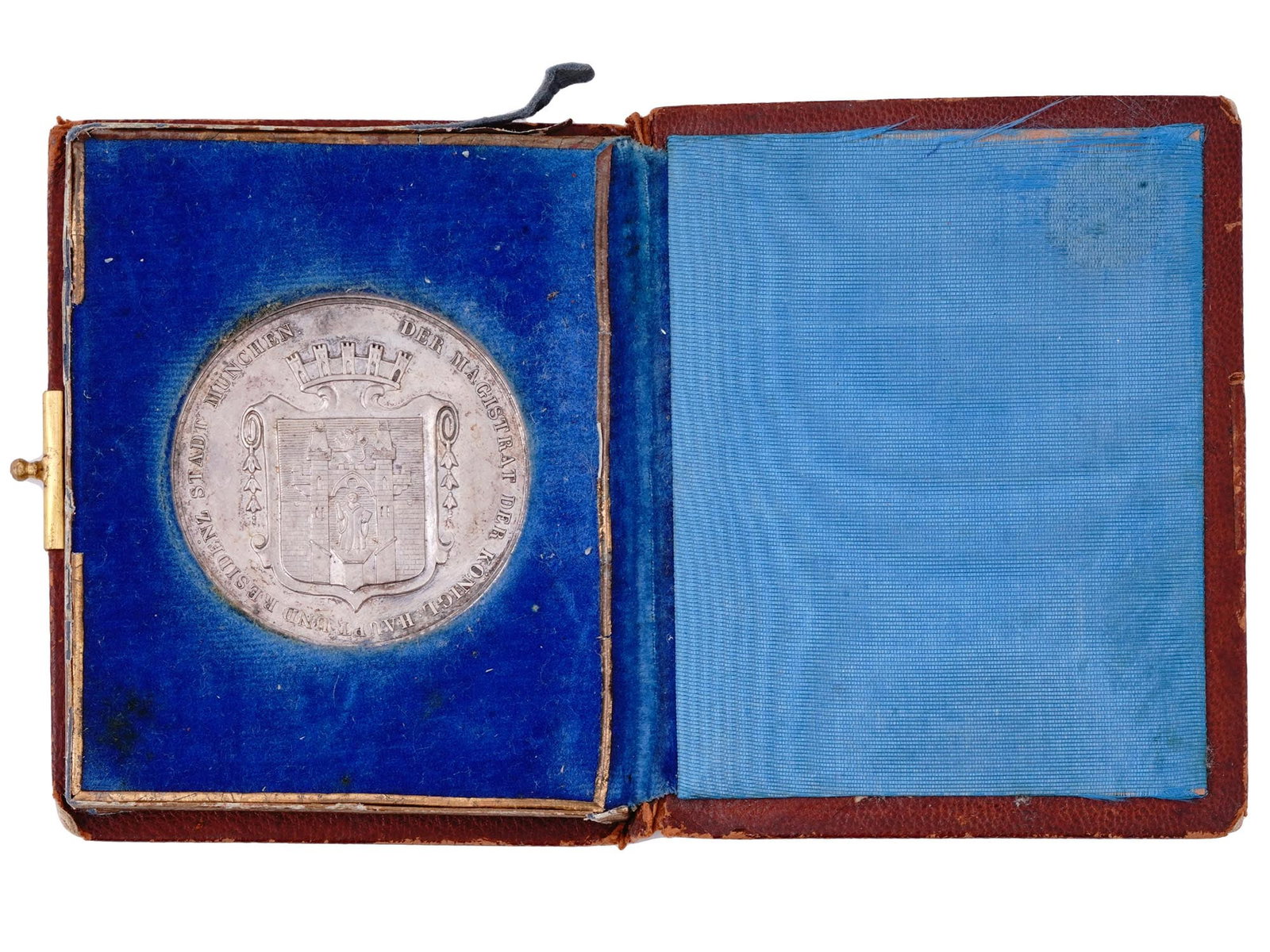 A CASED 1895 MUNICH LONG SERVICE TABLE MEDAL IN SILVER: A silver Munich table medal for long service presented in a brown leather-bound booklet case with the year 1895 in gold lettering on the cover. The medal displays the City of Munich Coat of Arms with 