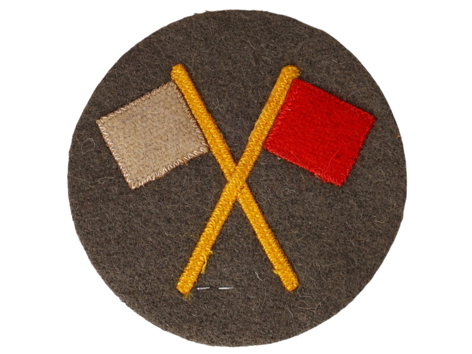 A GERMAN MILITARY MANEUVER CONTROL SLEEVE BADGE, WWI: Circular field-grey wool sleeve insignia embroidered with crossed signal flags, one white and one red, mounted on a matching wool backing. The reverse retains its original fabric construction.This ins