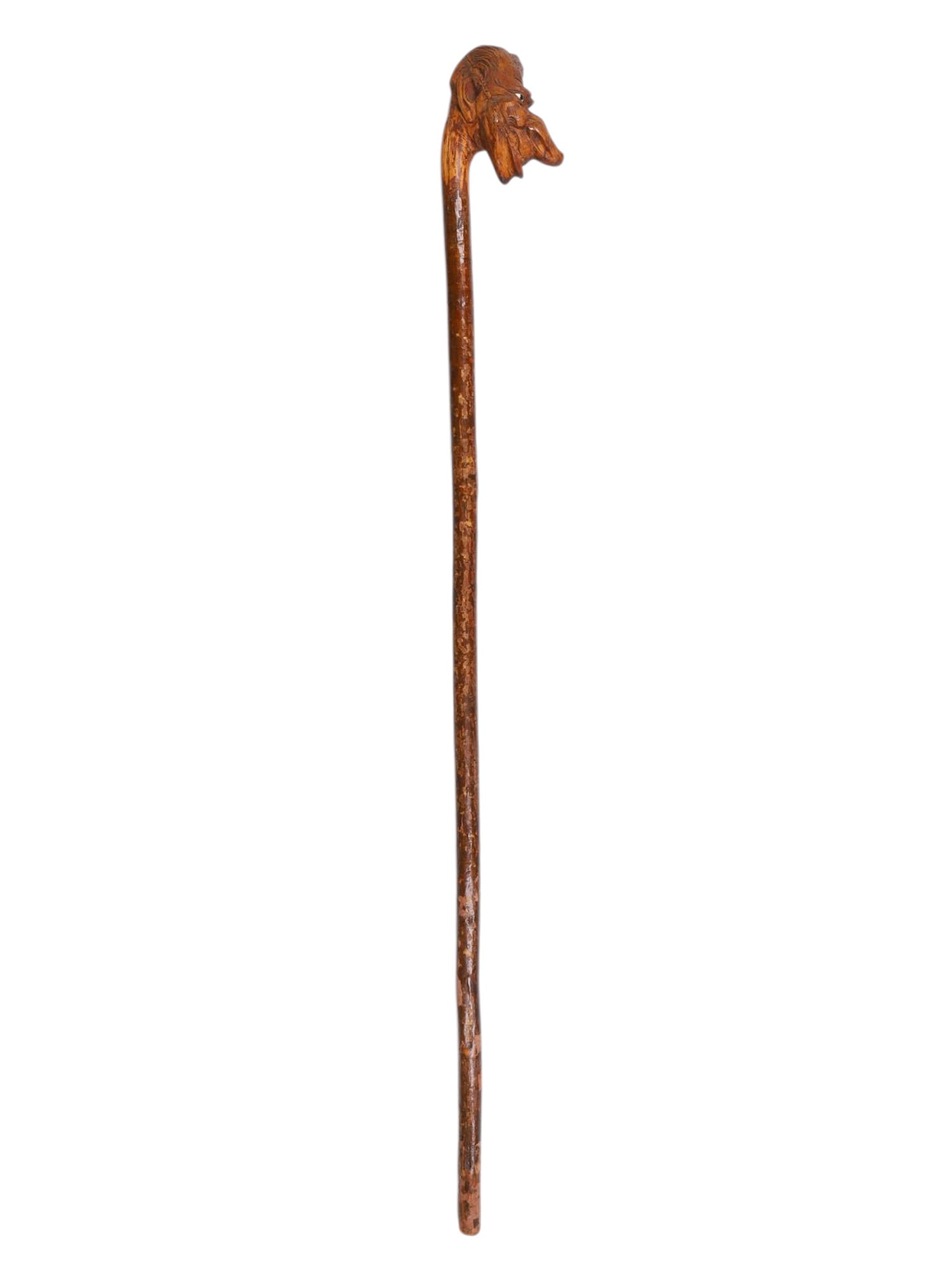A LARGE CARVED WOOD WALKING STICK WITH MYTHOLOGICAL MASKED HANDLE, LATE 19TH CENTURY: Carved from a single piece of dense hardwood, the long, tapering shaft is surmounted by a boldly sculpted handle in the form of a grotesque or mythological creature’s head. The face is rendered 