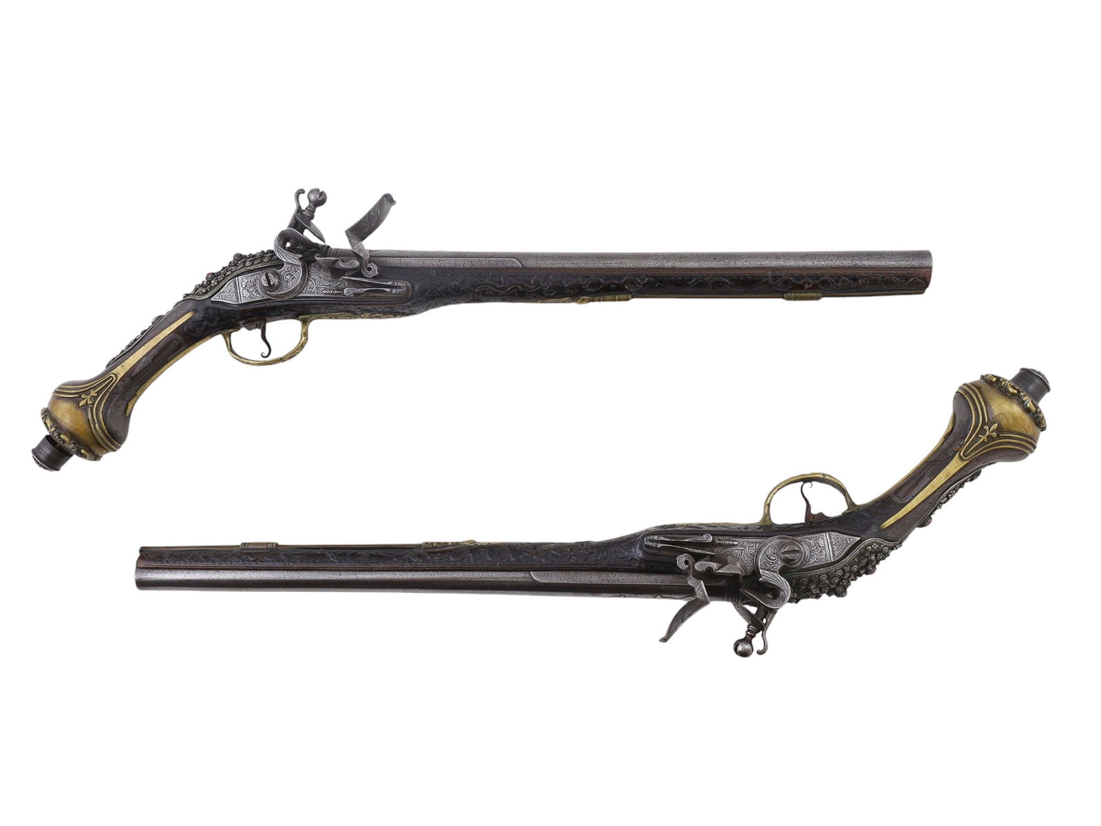 A PAIR OF MATCHED SILVER-MOUNTED DAMASCUS STEEL OTTOMAN FLINTLOCK PISTOLS, EARLY 19TH CENTURY: A fine pair of matched flintlock pistols from the Ottoman Empire with brilliant Damascus steel barrels with their patterning visible and in extremely good condition throughout their entire length. The