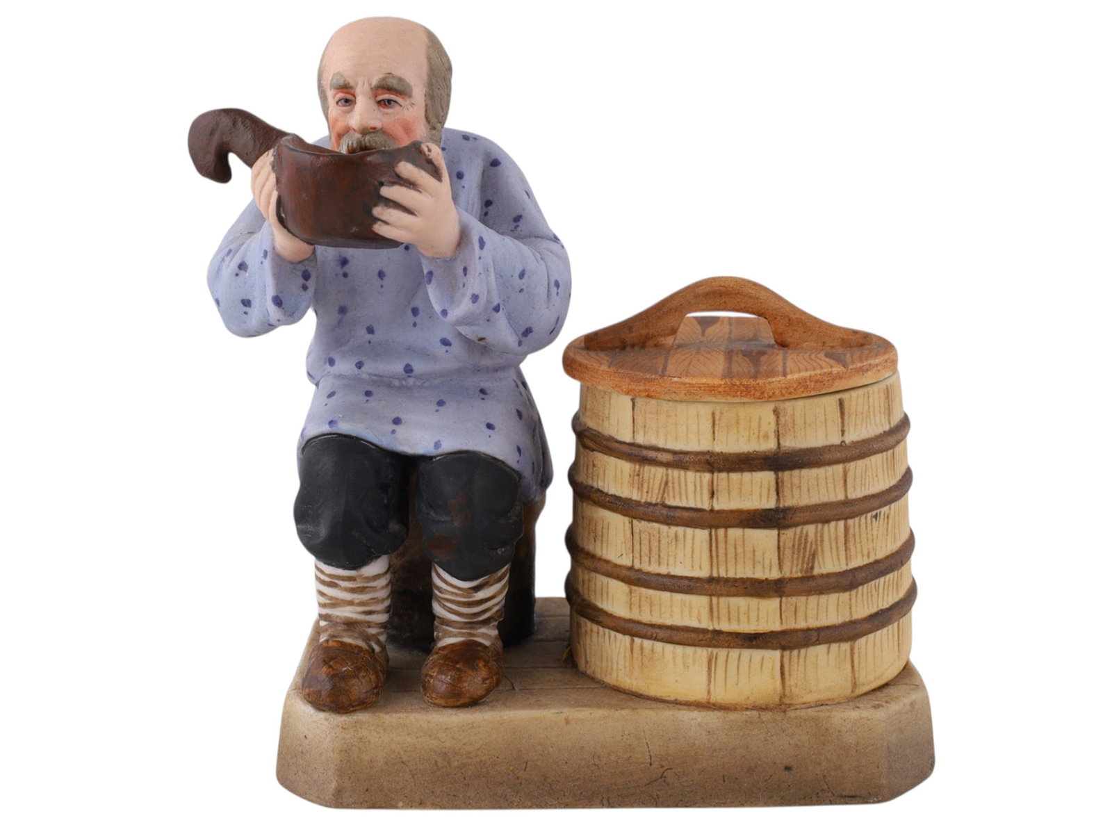 A SOVIET VERBILKI PORCELAIN FIGURAL COVERED SALT CELLAR, "THE PEASANT DRINKING FROM A KOVSH": Dmitrov Porcelain Factory, Verbilki, formerly Gardner, circa 1927–1932.After an earlier Gardner model, naturalistically modelled and polychrome-painted as a seated, bearded peasant drinking from