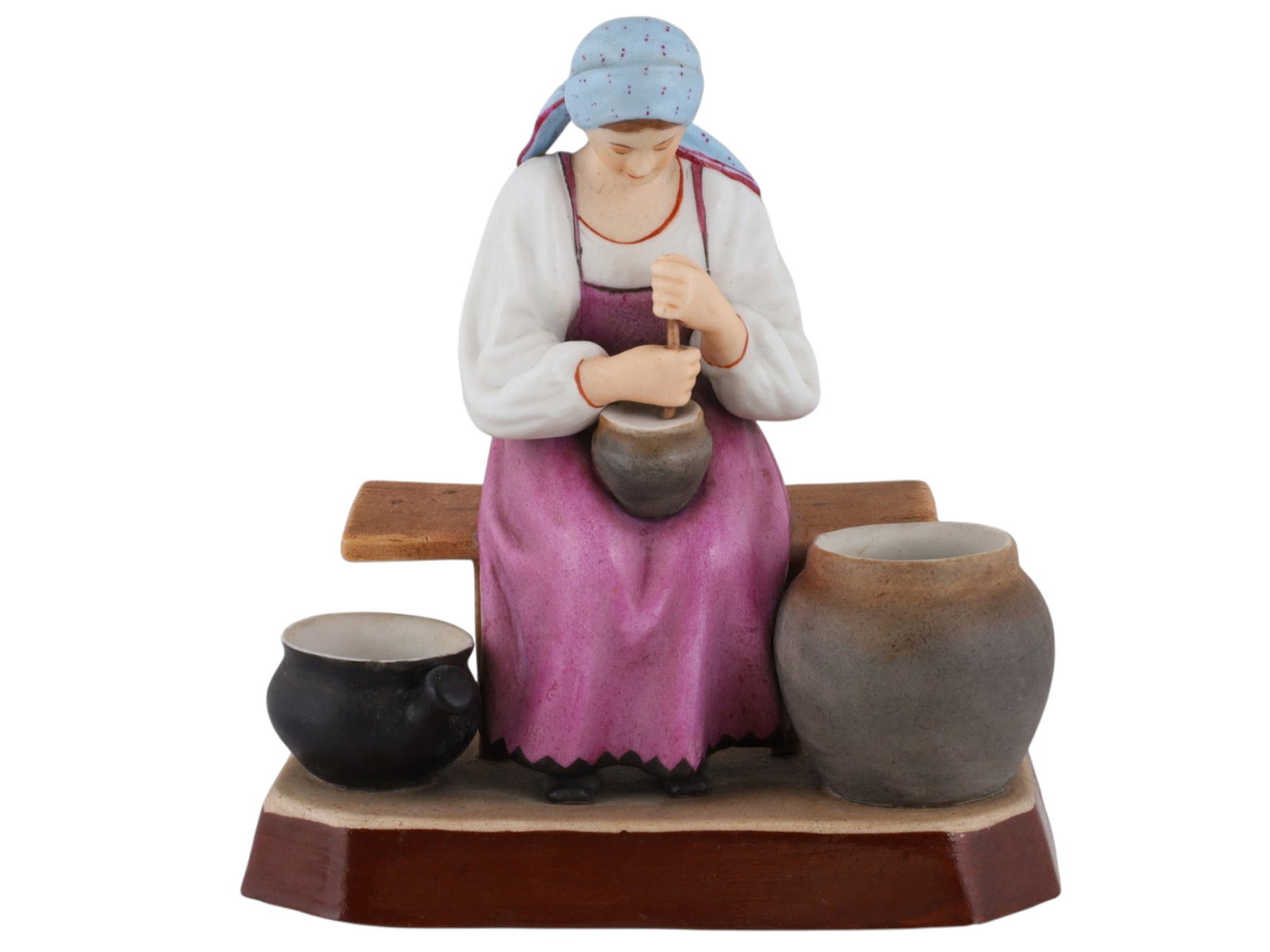 A RUSSIAN GARDNER PORCELAIN FIGURE OF A PEASANT WOMAN AT WORK, 19TH CEN.: A Russian porcelain figure of a peasant woman produced by the Gardner Porcelain Factory om the 19th century. The woman is depicted seated on a bench as she stirs or churns something in a pot in her la