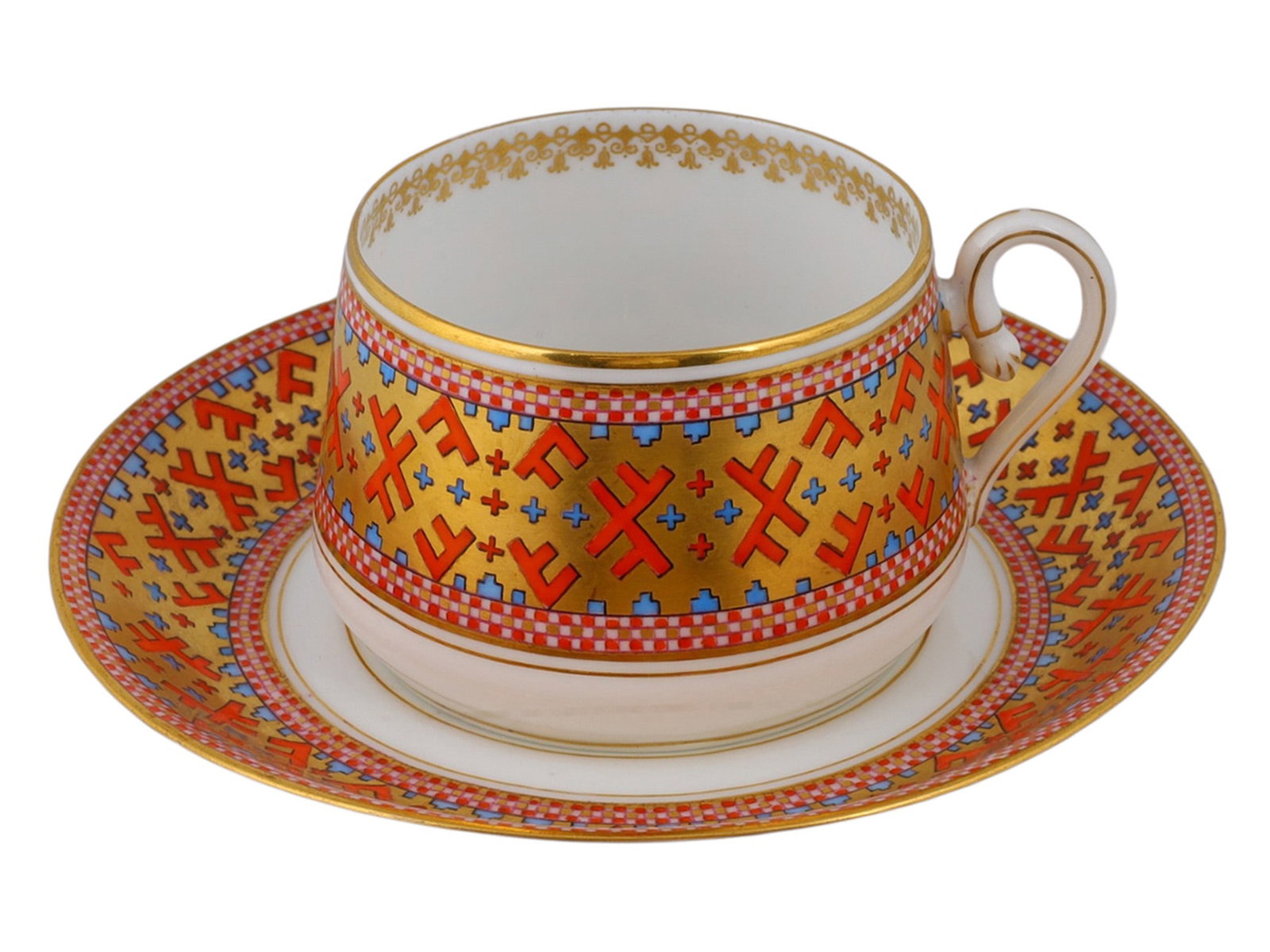 A RUSSIAN KORNILOV BROTHERS PORCELAIN CUP AND SAUCER BY THE KORNILOV BROTHERS FACTORY, ST.: The cylindrical cup with a loop handle, decorated with a broad gilt band of stylized red and blue geometric motifs inspired by Russian folk embroidery, framed by red and white chequered borders. The s