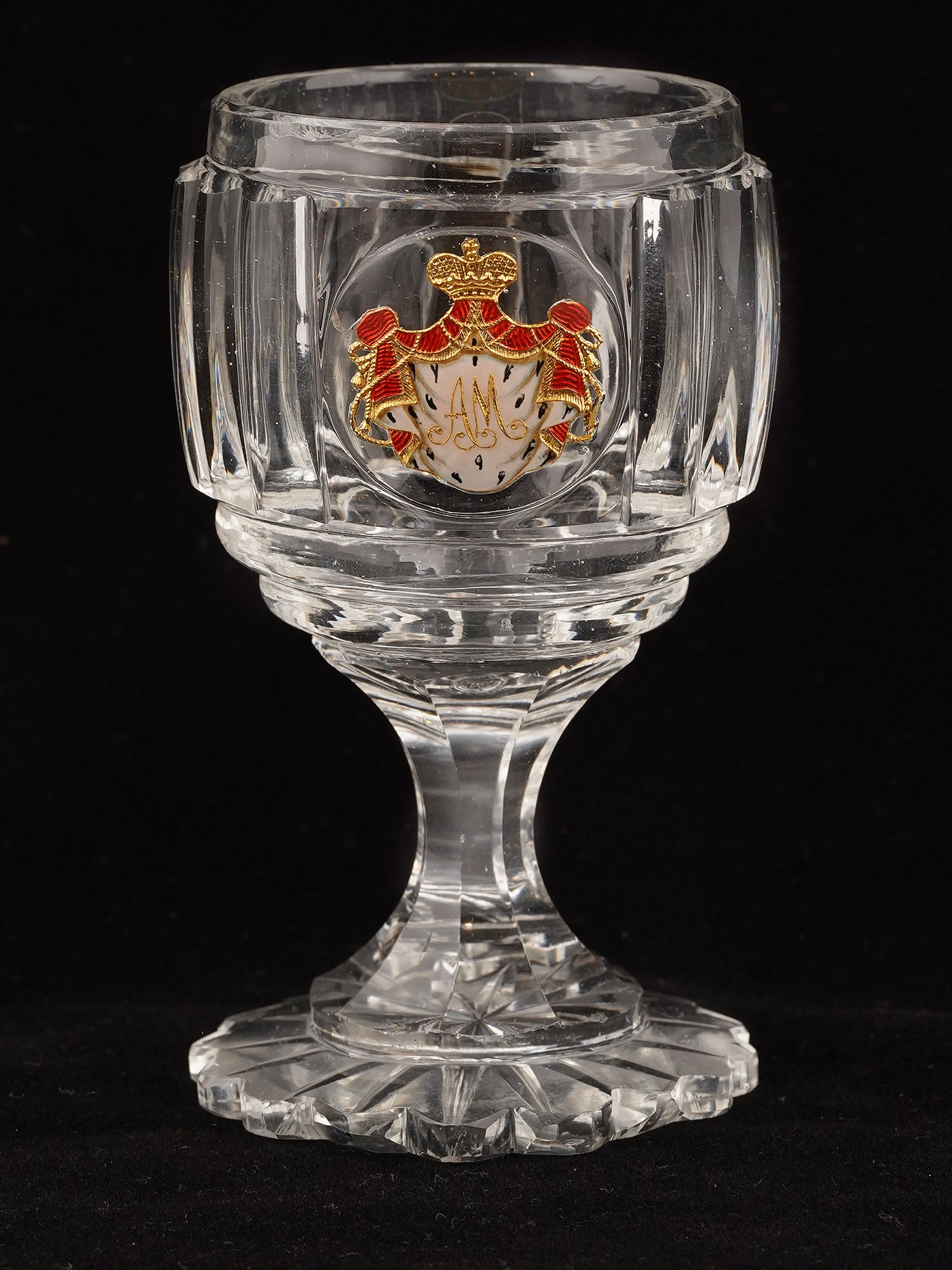 AN IMPERIAL RUSSIAN CUT-GLASS GOBLET FROM A BANQUET SERVICE, IMPERIAL GLASS FACTORY, ST PETERSBURG,: The heavy colorless crystal goblet with a lobed cylindrical bowl, faceted waisted stem and scalloped circular foot cut beneath with a radiating star. The bowl centers an enamel-painted gold-foil inclu