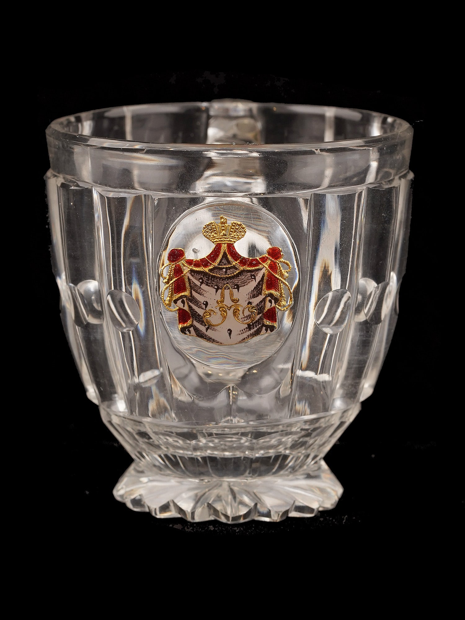 AN IMPERIAL RUSSIAN CUT-GLASS HANDLED CUP FROM A BANQUET SERVICE IMPERIAL GLASS FACTORY, ST: A faceted, heavy, colorless crystal cup with a slightly tapering body, an applied angular loop handle, and a scalloped foot cut underneath with a radiating star. The front centers an enamel-painted go