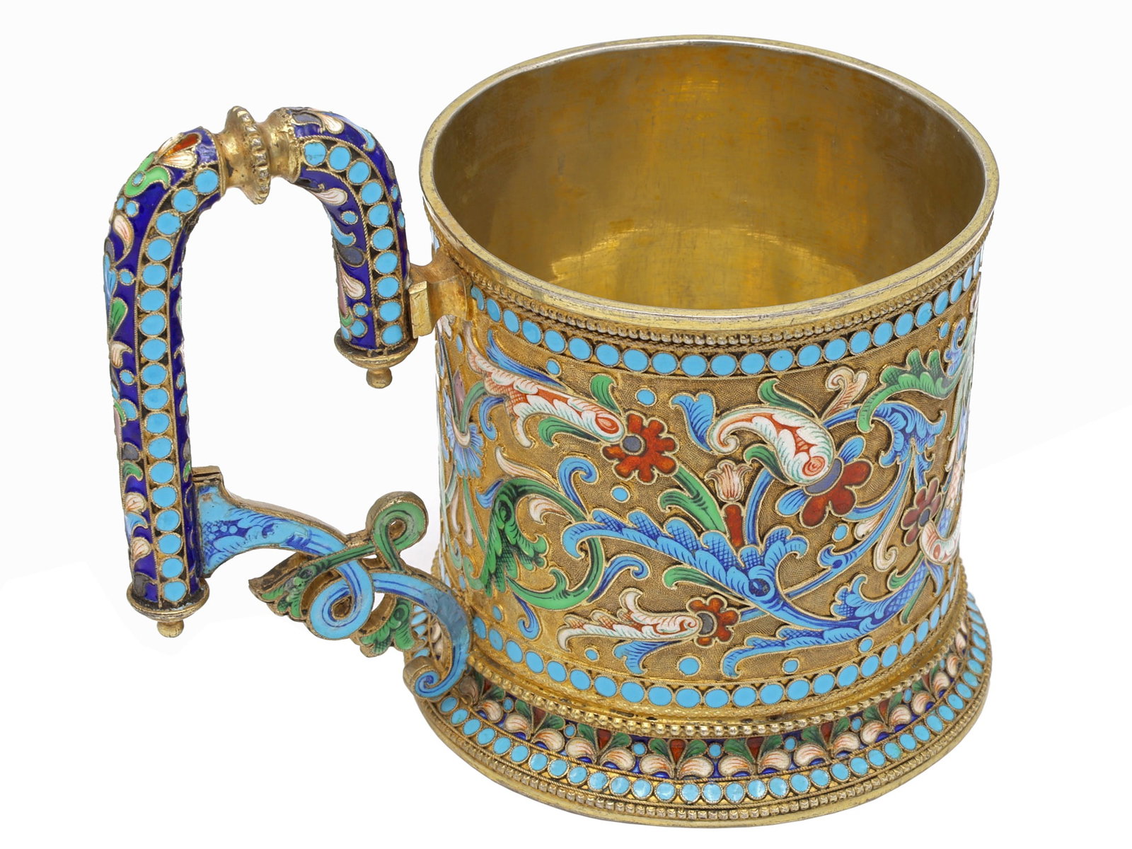 A RUSSIAN PARCEL-GILT SILVER AND CLOISONN? ENAMEL PRESENTATION TEA GLASS HOLDER: Of cylindrical form on a spreading circular foot, the body and angular handle are richly decorated in polychrome cloisonné enamel with scrolling foliage, flowerheads, and stylized palmettes in sh