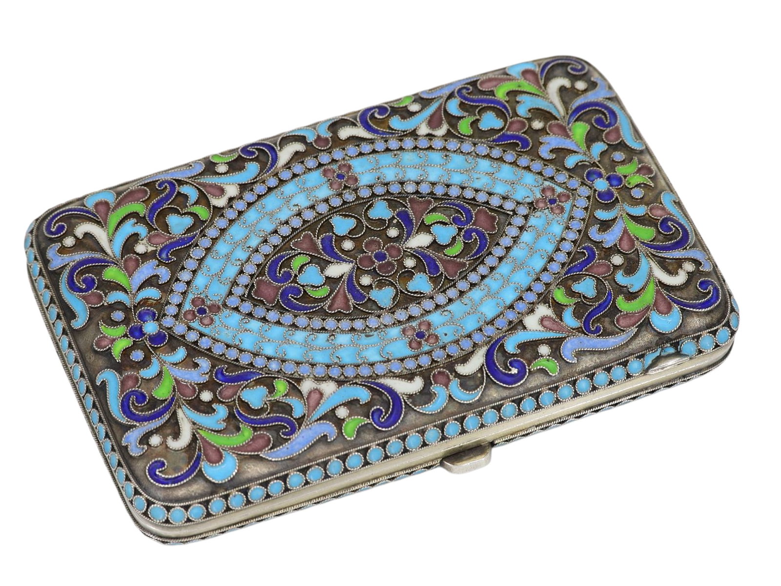 A RUSSIAN GILT-SILVER AND CLOISONNE ENAMEL CIGARETTE CASE, CA. 1880: Russian cigarette case with rounded edges and a hinged lid, fitted with a thumbpiece clasp. Both sides feature intricate scrolling foliate and floral patterns in turquoise blue, cobalt blue, green, wh