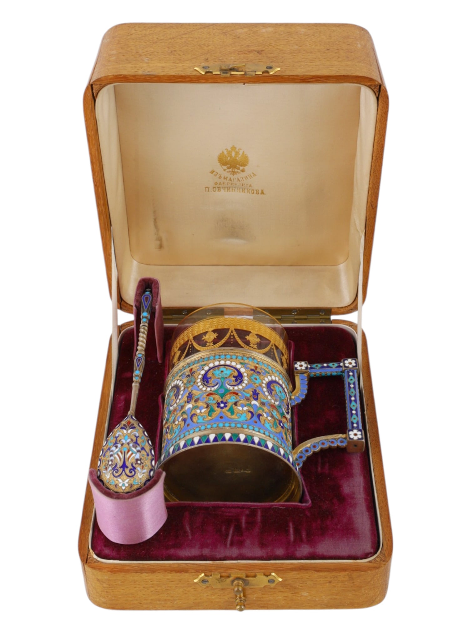 A CASED GILT-SILVER AND CLOISONNE ENAMEL TEAGLASS HOLDER, 1896 BY OVCHINNIKOV: The cylindrical holder decorated with polychrome scrolling foliage and flowerheads in turquoise, blue, green, white, mauve and red cloisonne enamel, raised on a spreading geometric-enamel foot and fit